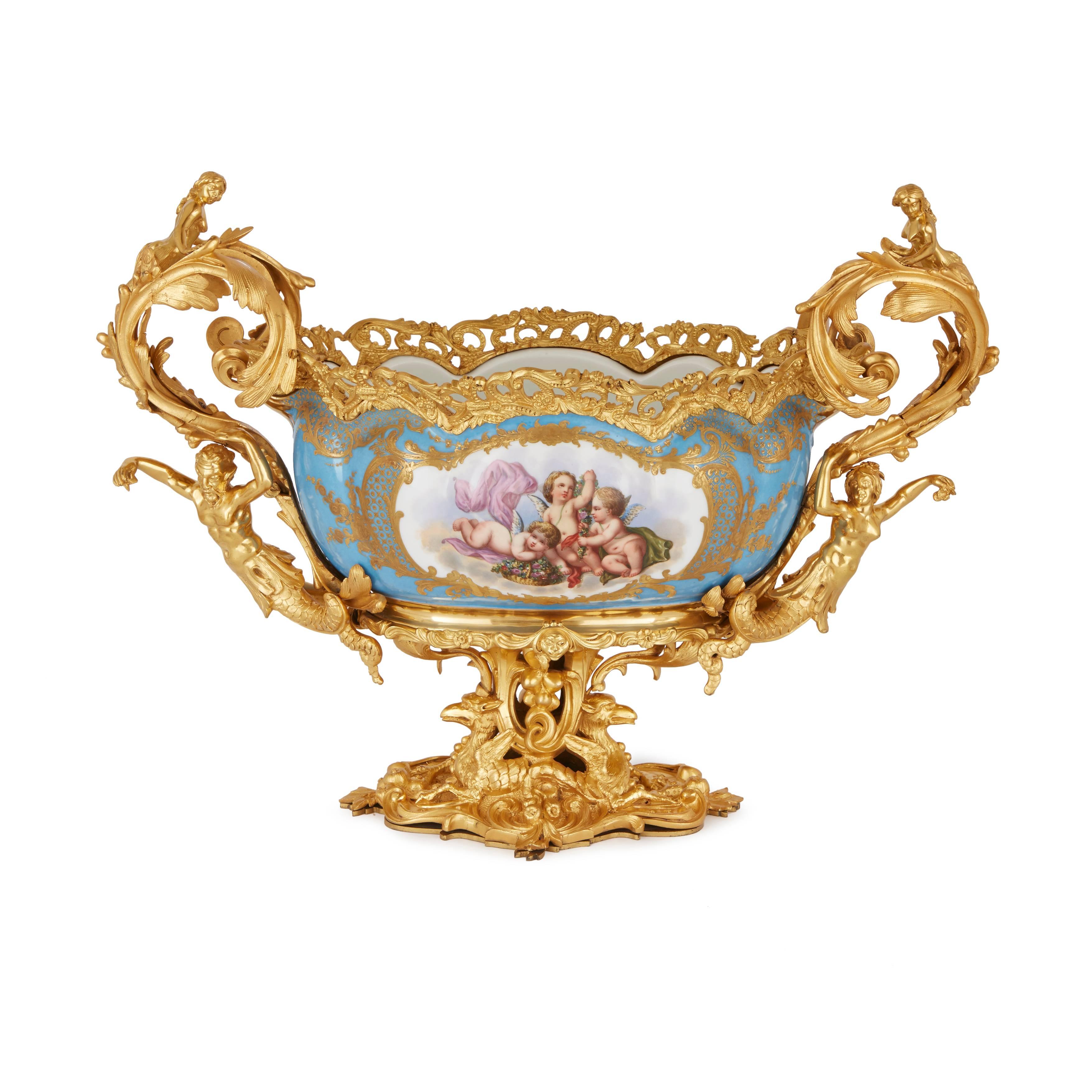 The body parcel-gilt on light blue ground and finely painted with cherubs, the acanthus leaves twin handles supported by sirens, resting on an ormolu base decorated with griffins.