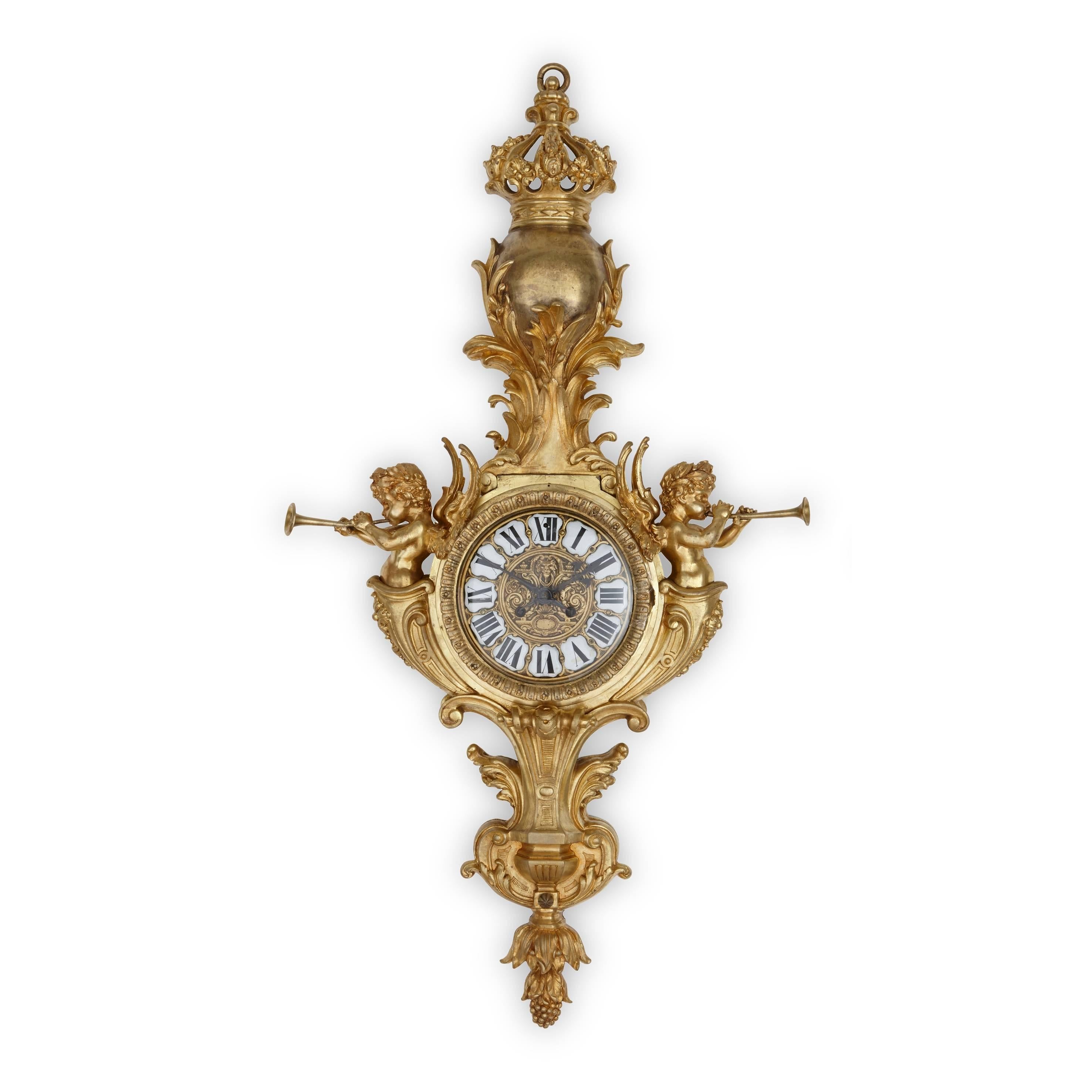 Manufactured in the Louis XVI style, both clock and barometer are encased within an ormolu case and flanked on either side by trumpet wielding cherubs, each surmounted with a patinated bronze sphere that is topped with a crown, the bases terminating
