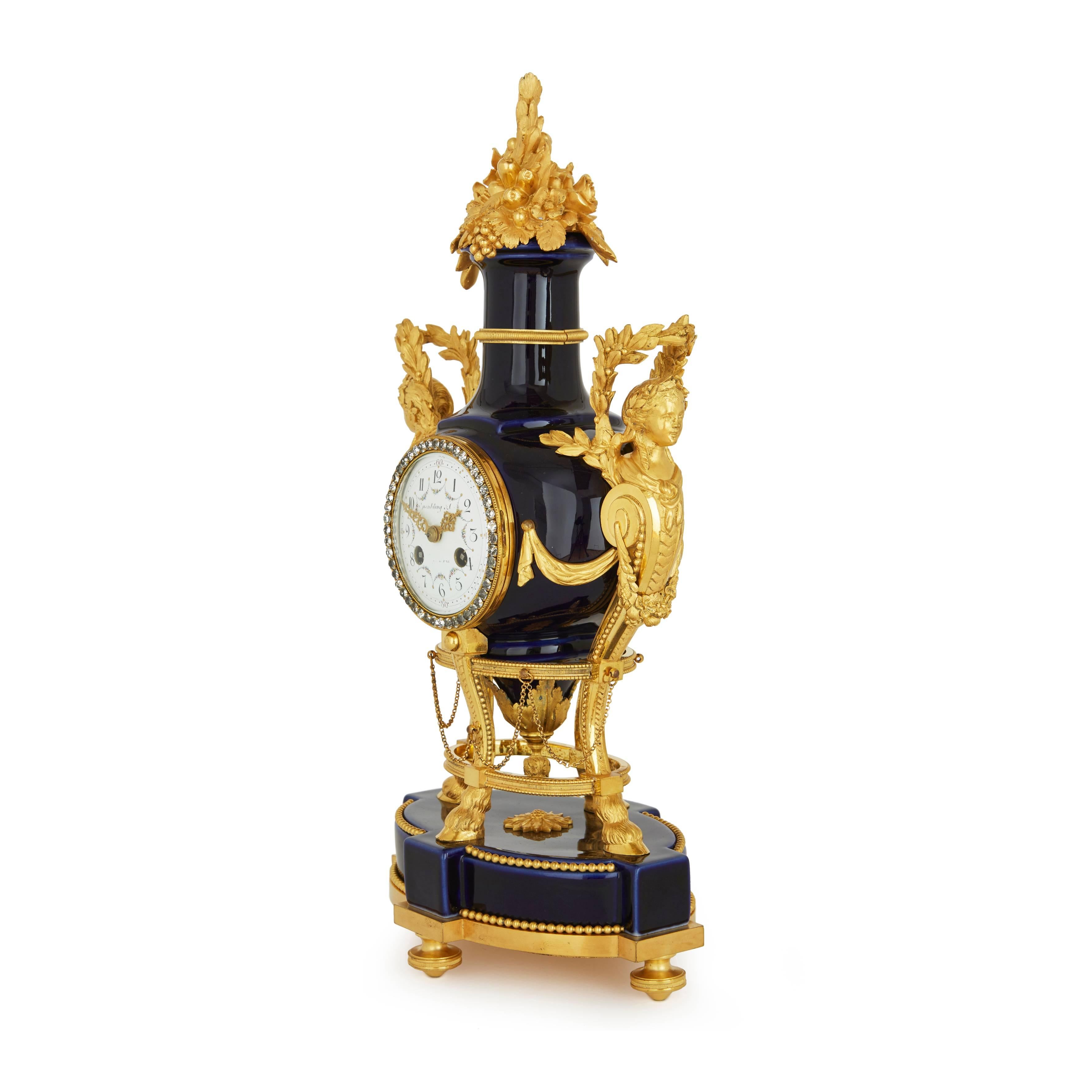 Comprising a central clock and a pair of flanking candelabra, the clock with central circular enamel dial with partially rubbed signature 'Spaulding & Co. Chicago & Paris' with a paste-set border, set within a dark blue porcelain case shaped