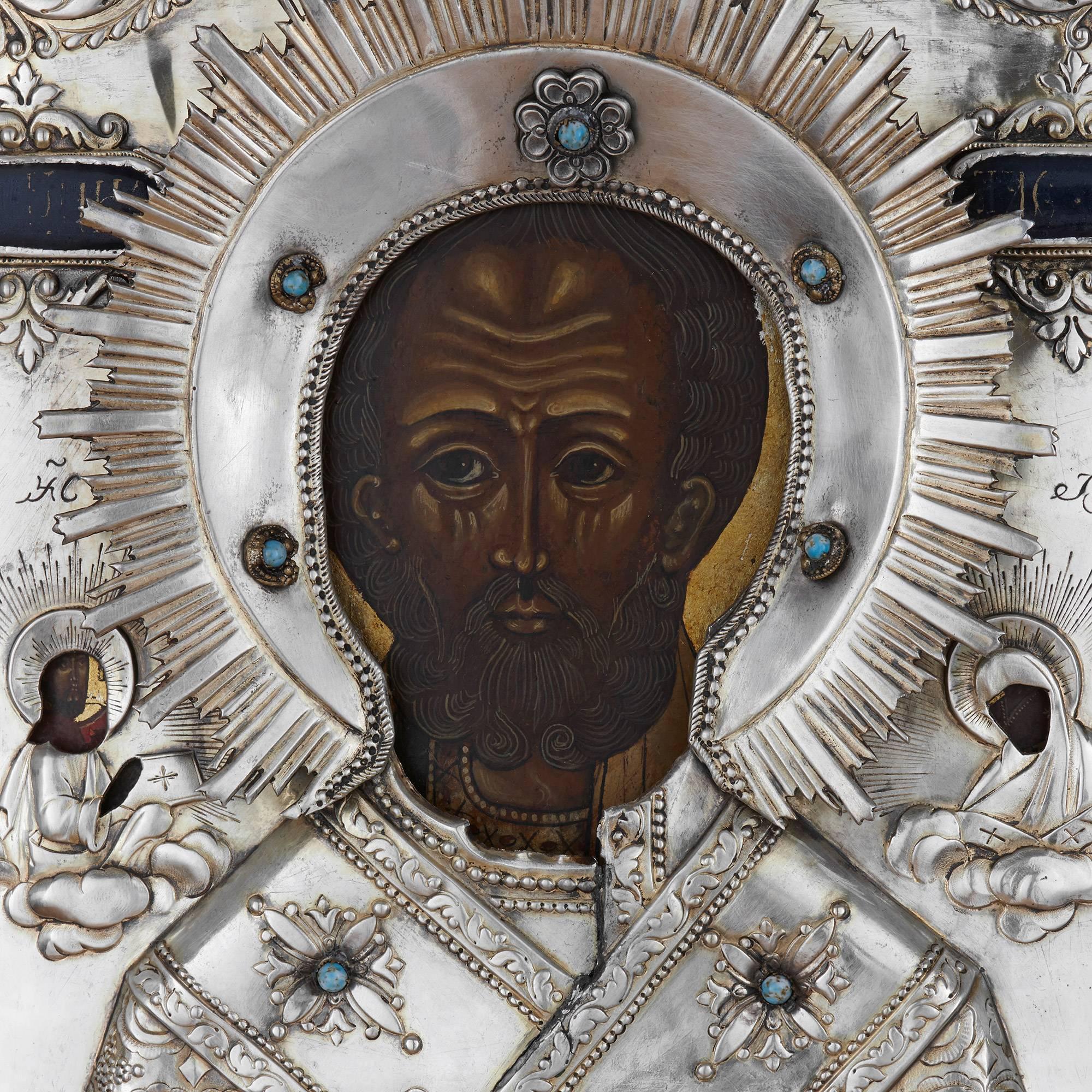 Depicting St. Nicholas at the centre, his right hand raised making the sign of the cross, his left hand holding a Bible; the icon covered by a protective silver oklad.

This stunning antique icon, although crafted in the typical Russian Orthodox