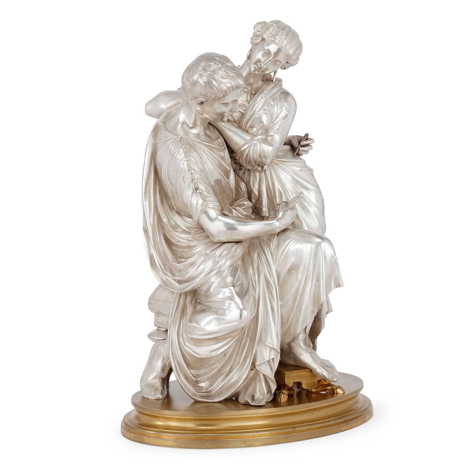 Depicting a moment of tender intimacy, this antique French bronze sculpture shows a couple in a moment of calm repose. Dressed in typical Classical Roman attire, the man sits, holding a tablet in front of him, which he gazes down at. The woman, also