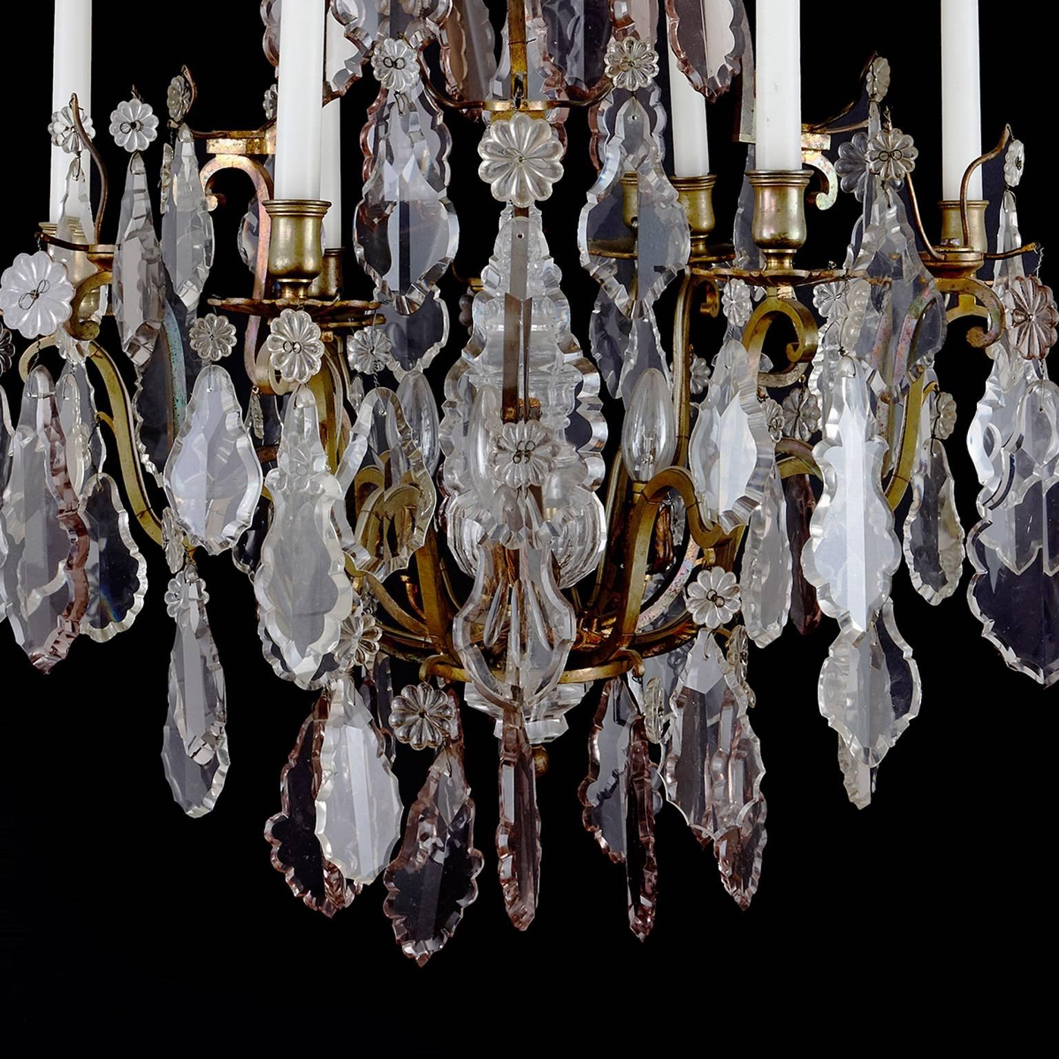 This spectacular French antique chandelier is composed of an impressive ormolu (gilt bronze) central structure that issues six scrolling branches for the lights. Covering the structure are multiple large, cut-glass droplets surmounted by elegantly