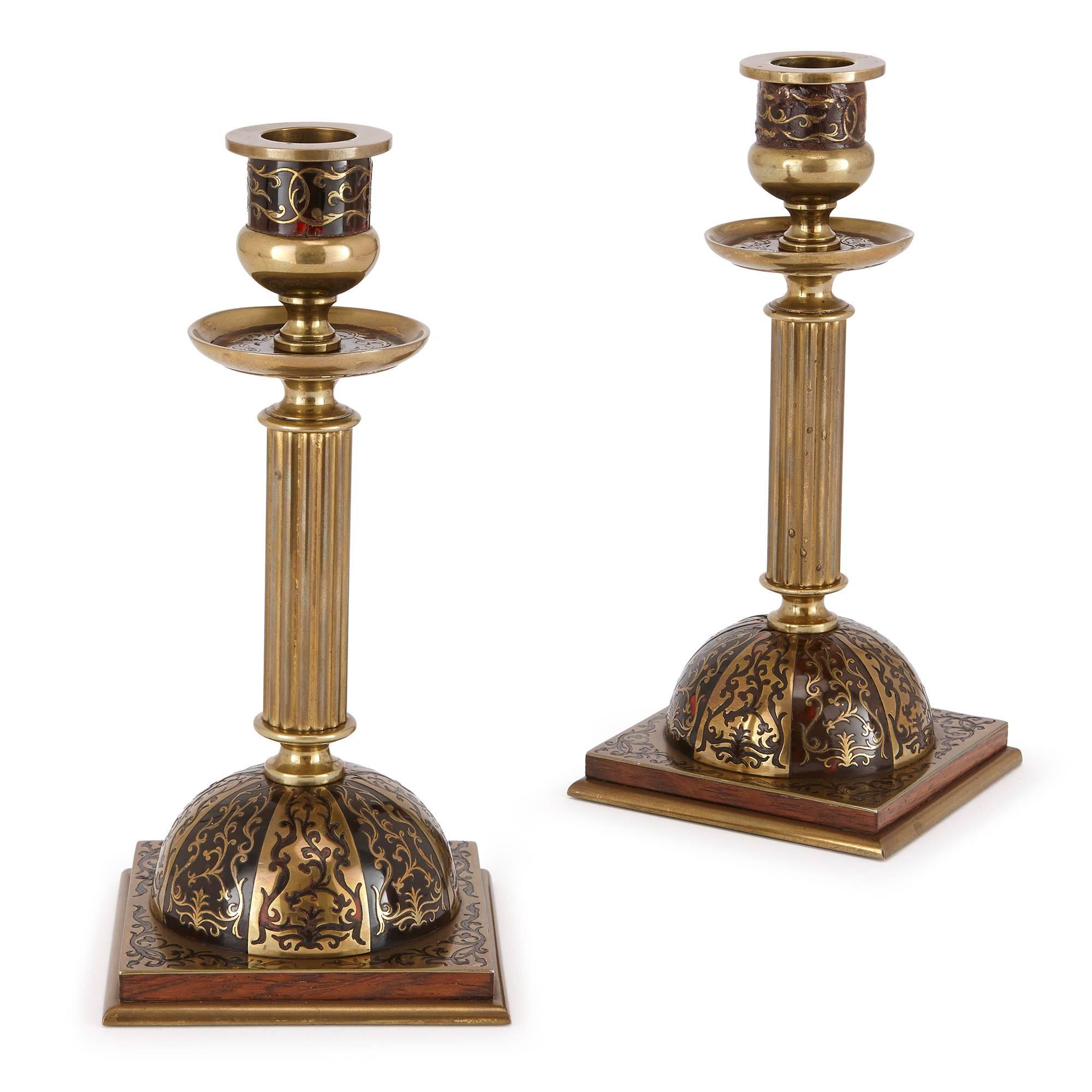This fine pair of brass candlesticks are masterfully cast, with decorations in the style of French cabinetmaker Andre Charles Boulle. The candlesticks are set into semi-spheres on square bases, which are decorated in alternate styles of marquetry:
