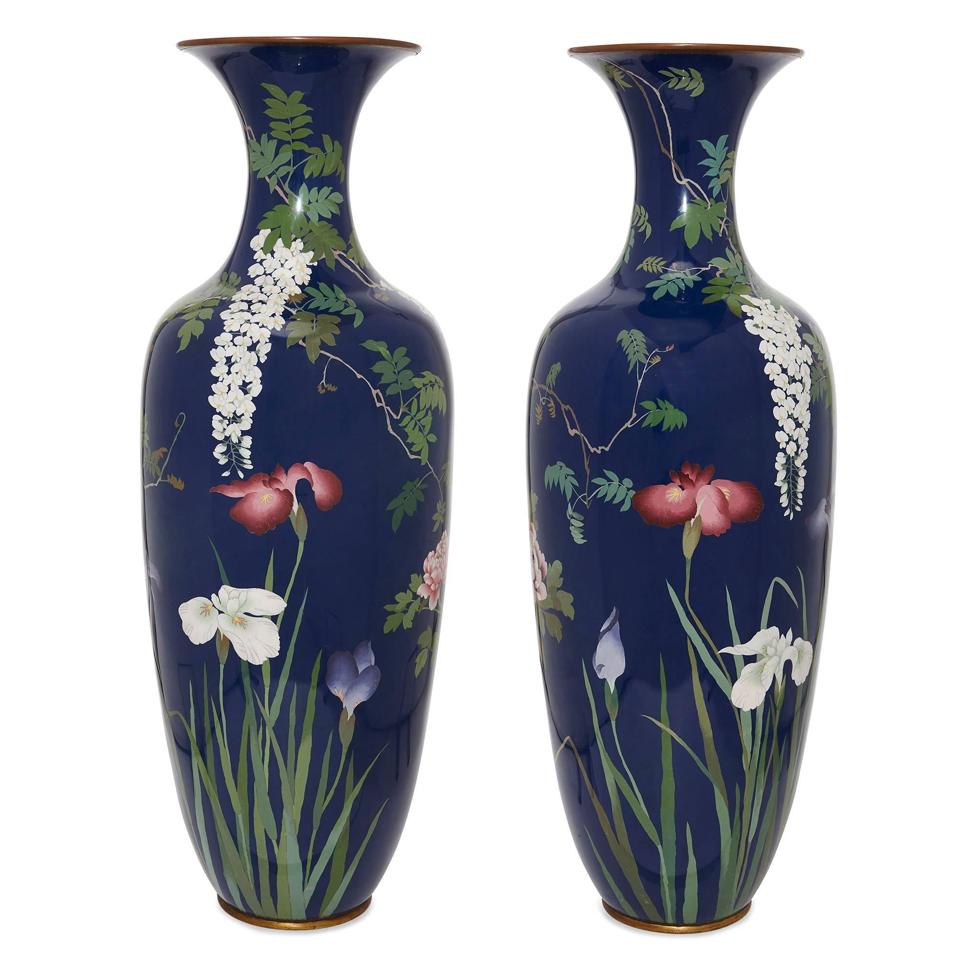 This pair of statuesque cloisonne enamel vases were made during the Japanese Meiji period in the late 19th century. The vases are ovoid in shape, and set with a blue ground. Their polished surfaces are adorned with foliate scenes of trees, birds and