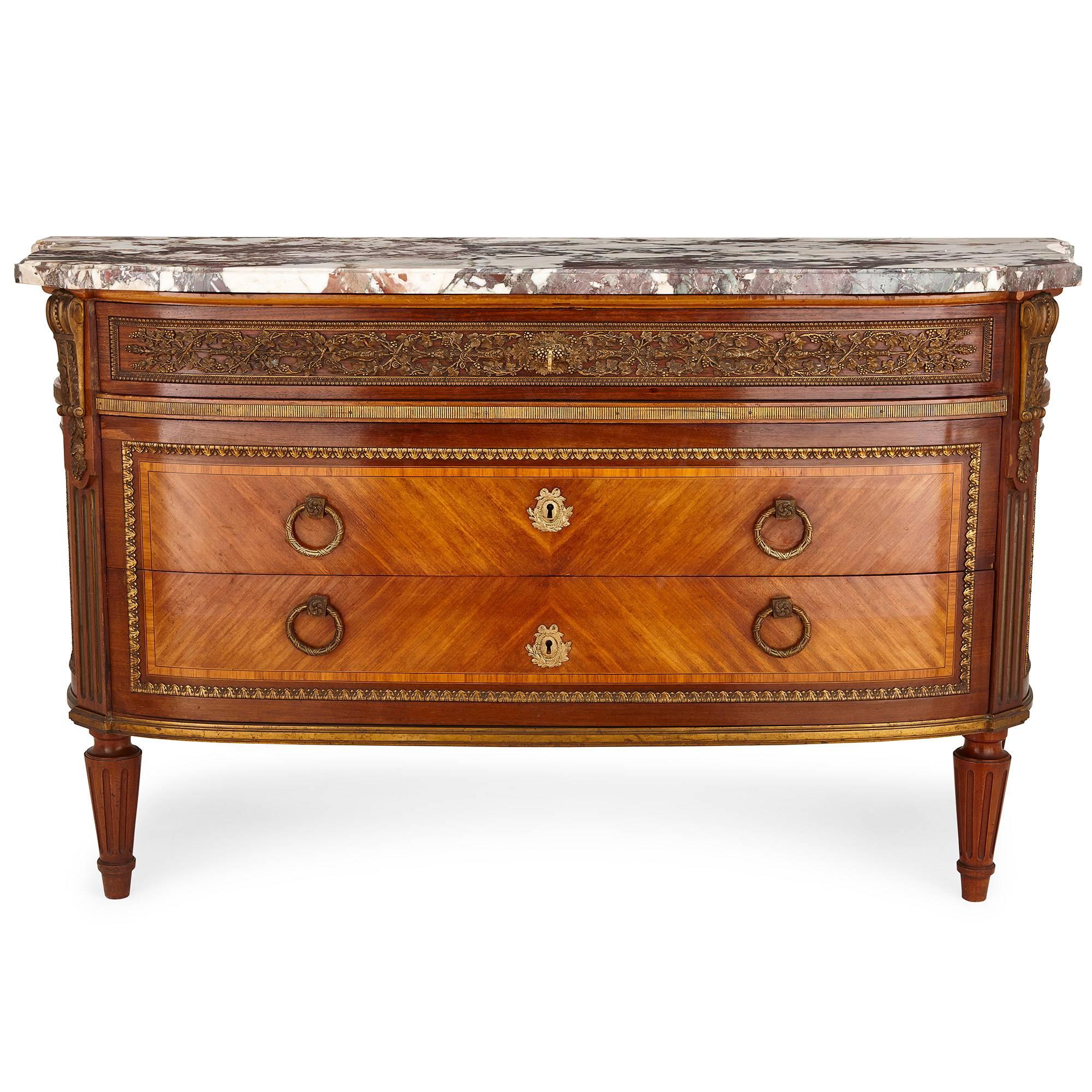 This fine, imposing French commode is based on a design by celebrated 18th century cabinetmaker Jean-Francois Leleu (French, 1721-1763). The commode is of mahogany, in rectangular shape with a slightly curved front. The top of the commode is mounted