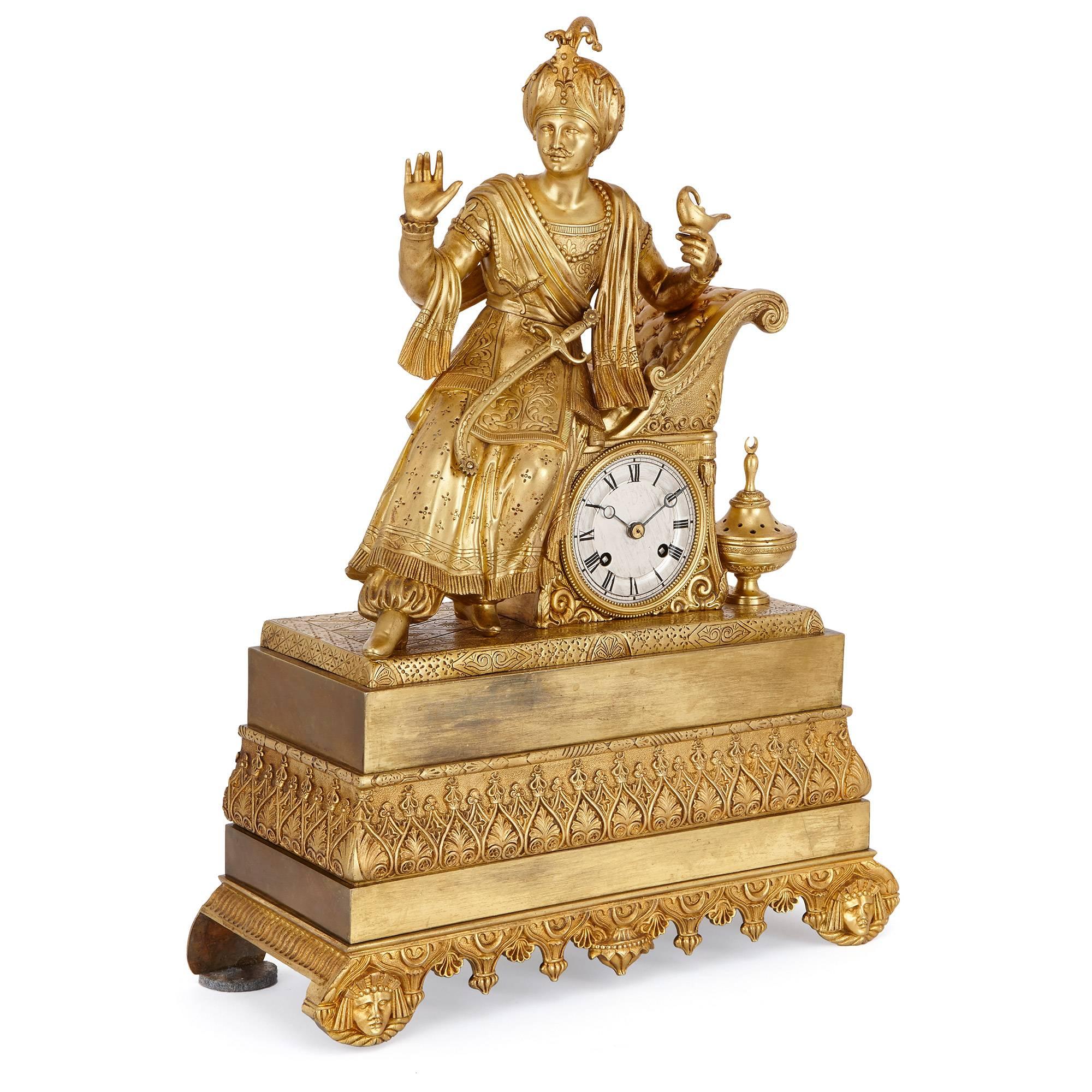 This striking and highly detailed mantel clock is made entirely of ormolu, and is surmounted by the figure of an Eastern nobleman. He wears typical dress of his location and period: finely detailed robes, a curved sword and a turban. He holds a lamp