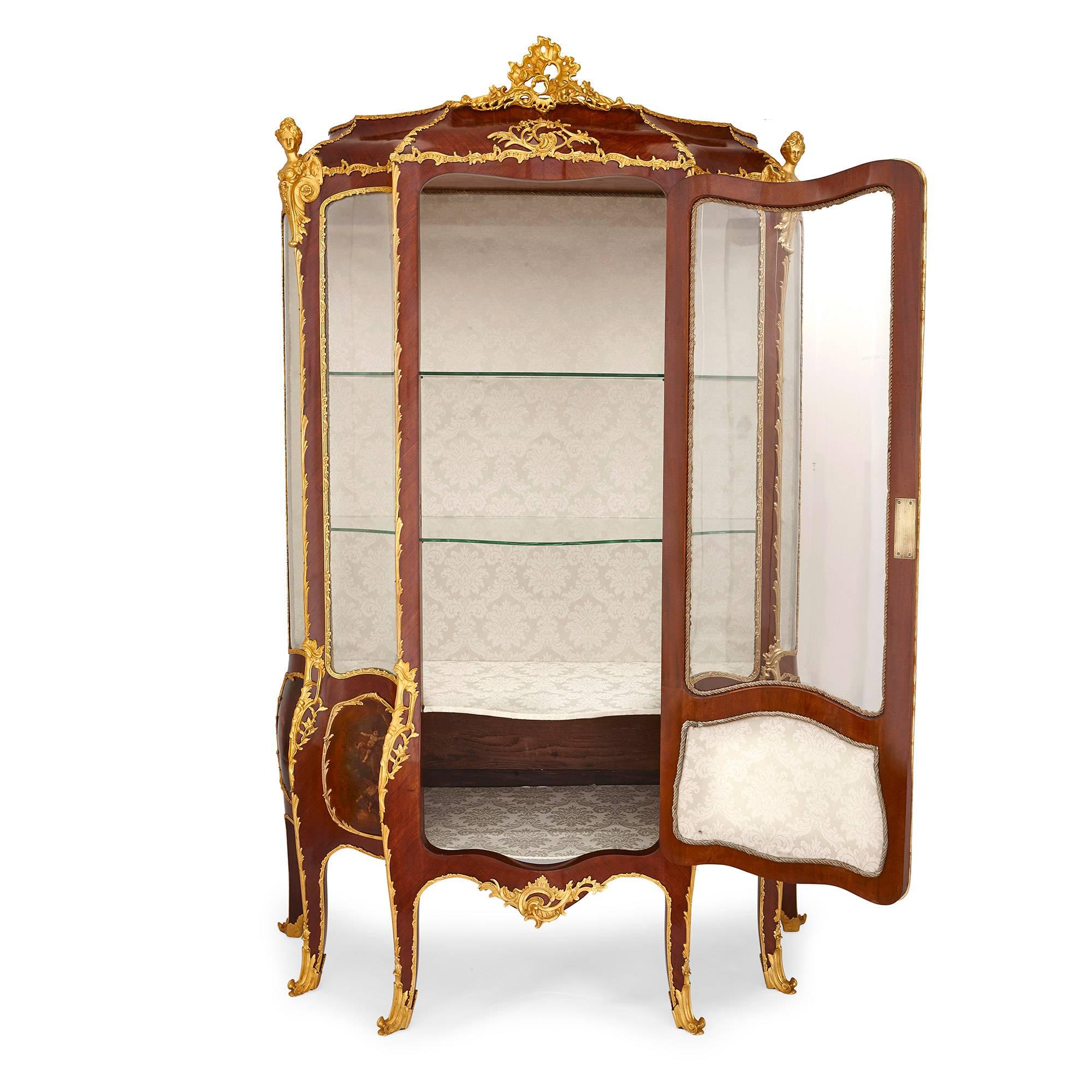 This exquisite French display cabinet is crafted from mahogany and features lustrous Vernis Martin lacquer decorations. The shape of the vitrine is striking: crafted in five vertical panels which undulate between convex and concave, it references a