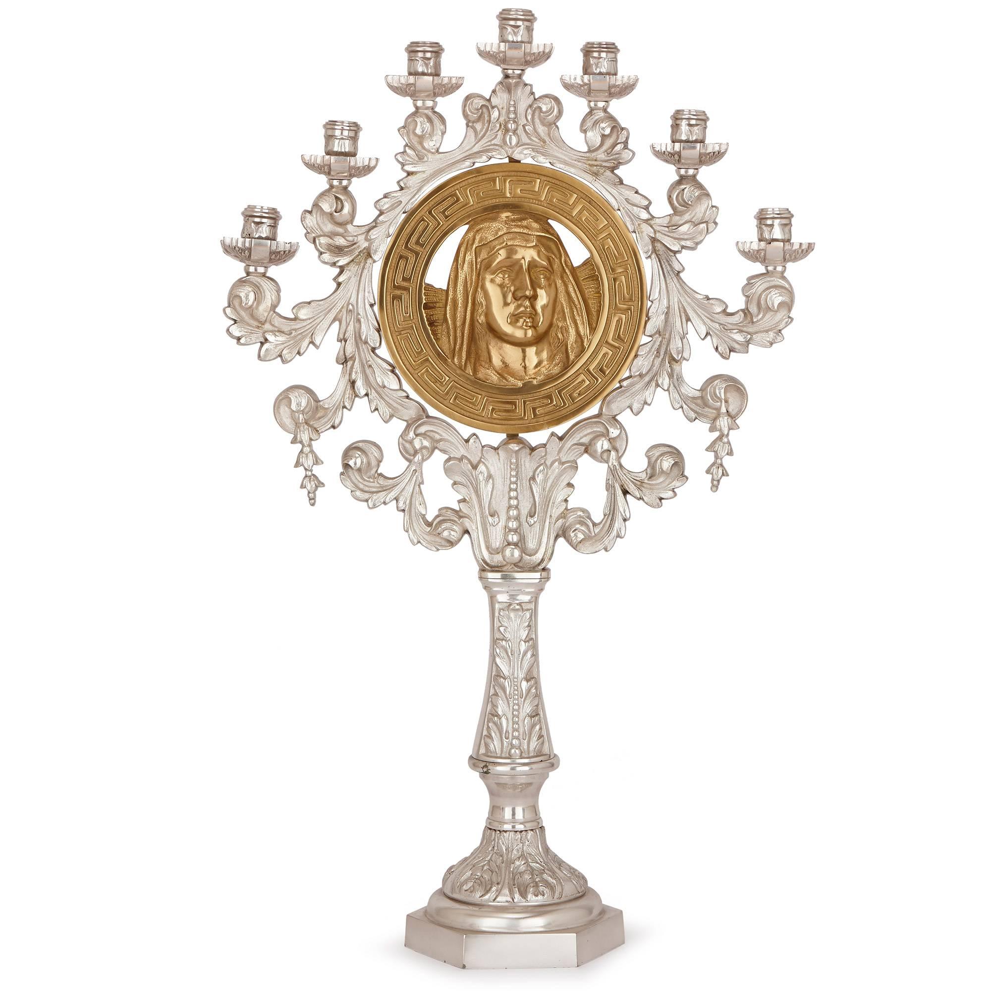 These striking and unusual candelabra each depict a portrait of Jesus and the Madonna in gilt bronze to the center. Each portrait is bordered by a gilt geometric circular pattern, further surrounded by a circular wreath of acanthus leaf in silvered