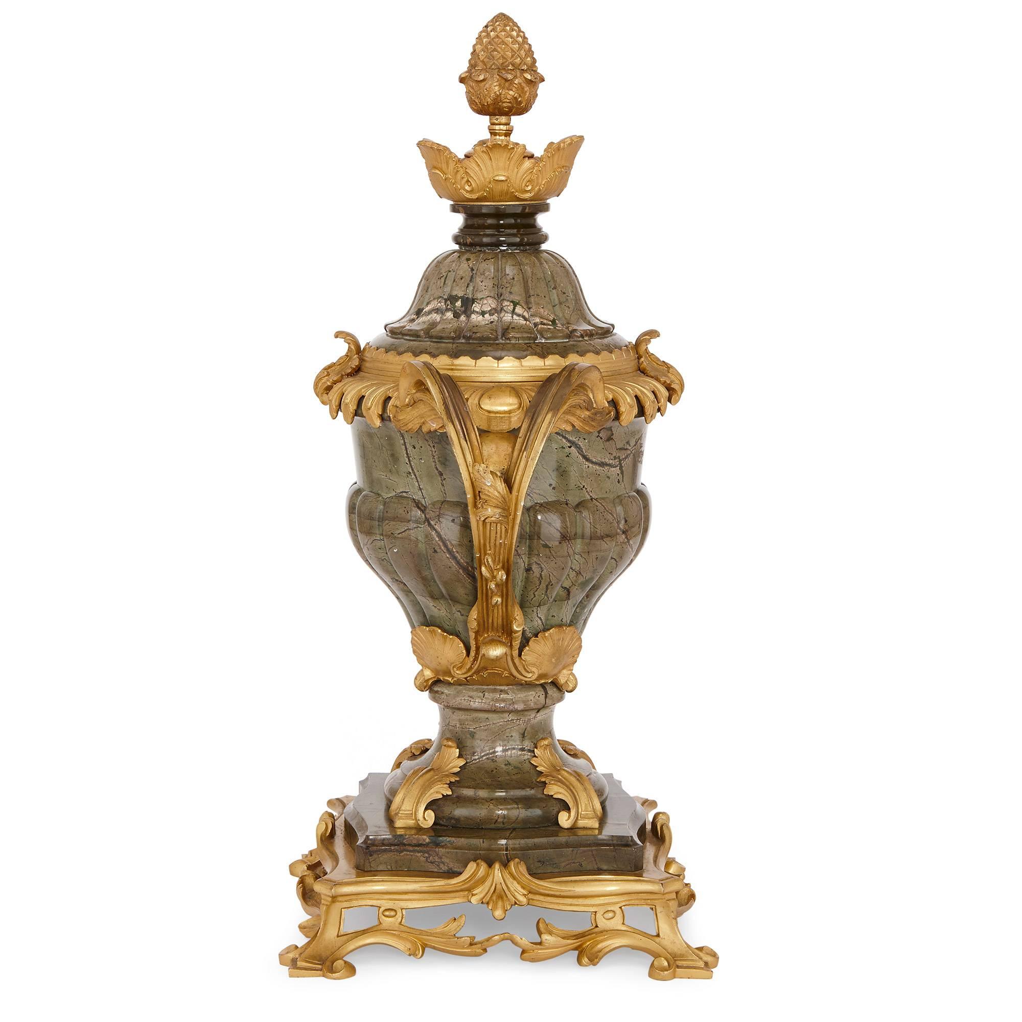 This exuberantly designed lidded urn is carved in veined green marble. The body of the urn is of canted ovoid shape and mounted with twin acanthus leaf ormolu handles. The body of the urn features fluting which tapers inwards towards the waisted