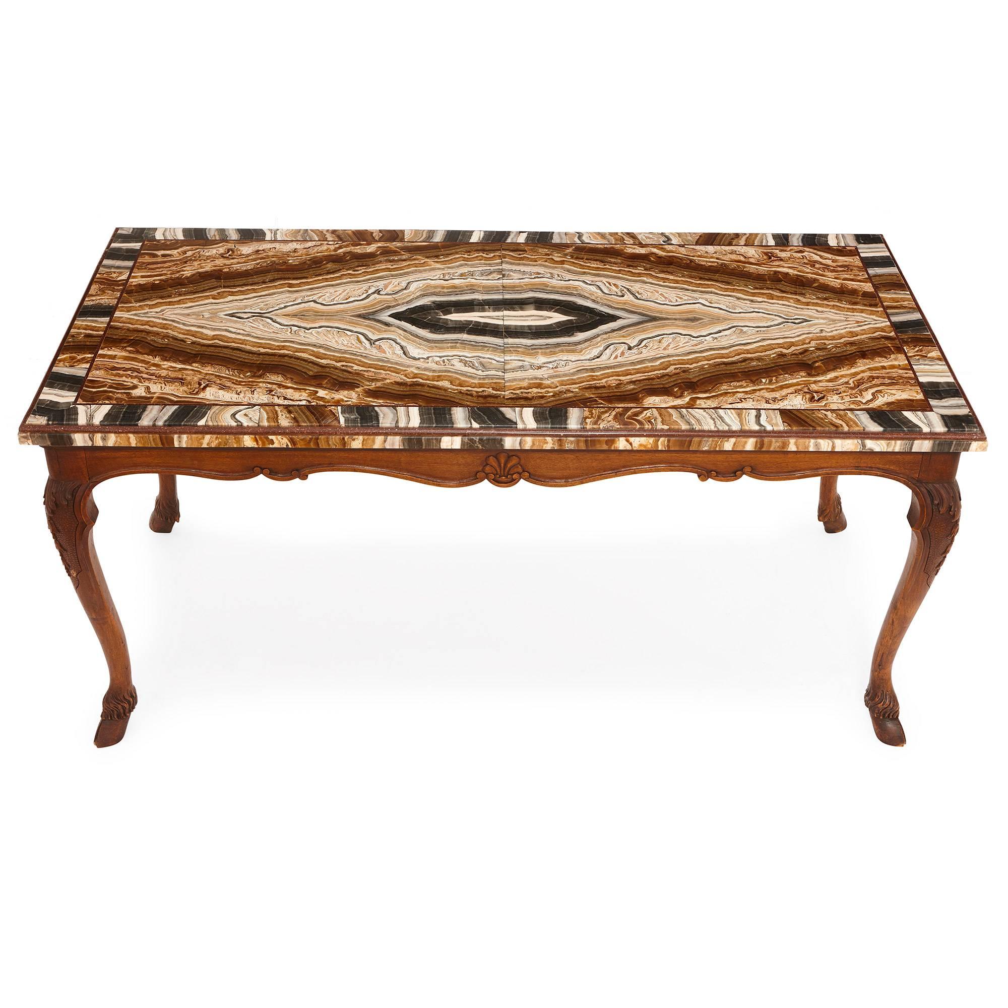 This coffee table was created in Italy in the 18th century. It features a rectangular top, which is crafted from onyx and edged with porphyry. This table top is composed of bands of colours, including black, grey, white, brown and orange. This top