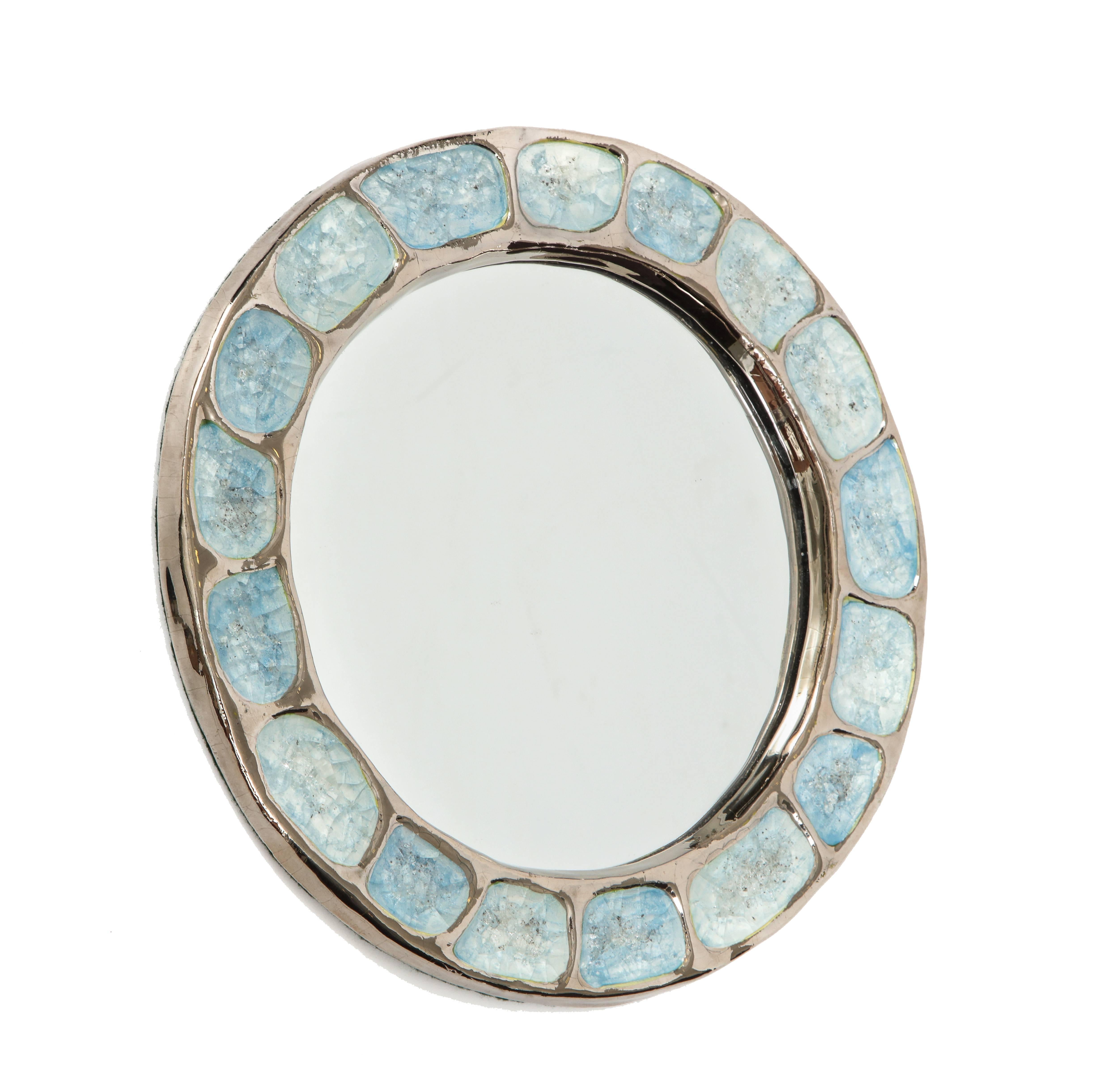 Miroir en céramique Francois Lembo argent métallique chrome bleu rond, France, années 1970. Miroir circulaire avec un décor en verre fusionné bleu clair contrasté par une glaçure argentée métallique. Dos sensible.