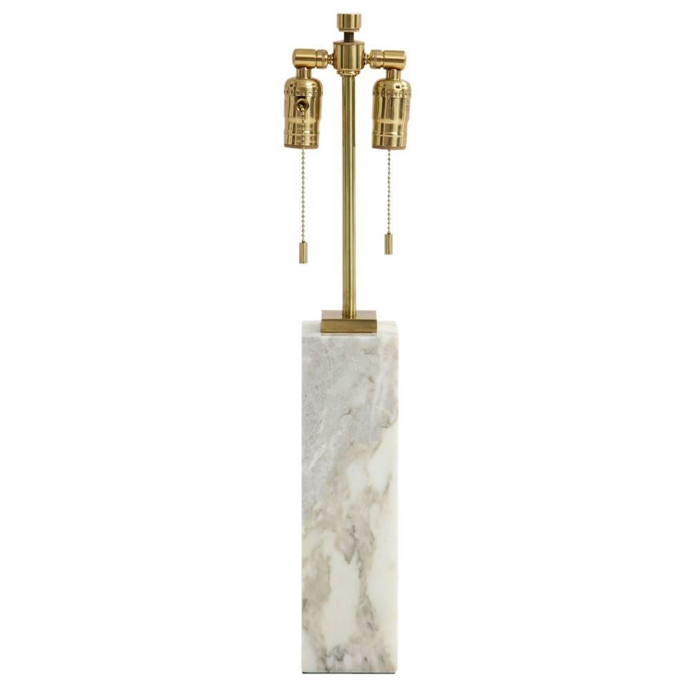T.H. Robsjohn-Gibbings for Hansen table lamp, white marble and brass. Small to medium scale table lamp in white and gray Carrara marble with brass two light cluster. The marble base measures 12 inches x 3.38 inches on each of the 4 sides. Photo 8 is