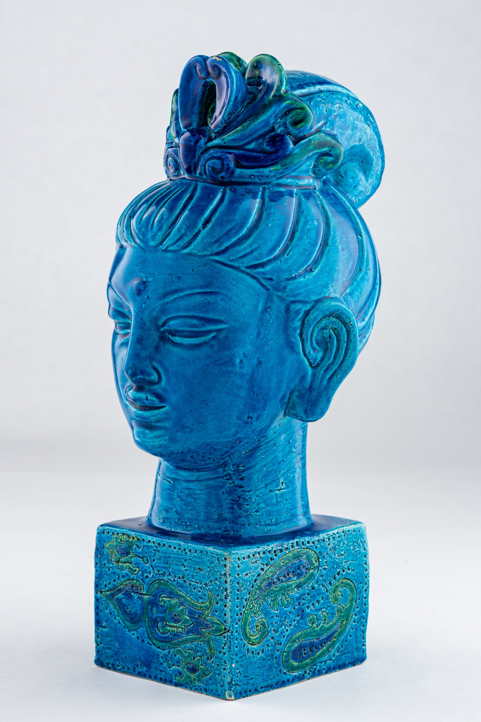 Bitossi Kwan Yin Buddha Bank, Ceramic, Blue Paisley, Signed. A beautiful and calming female Buddha glazed in a royal blue, with a hint of green in her hair, and having a square base decorated with psychedelic 60's abstract paisley embellishments.