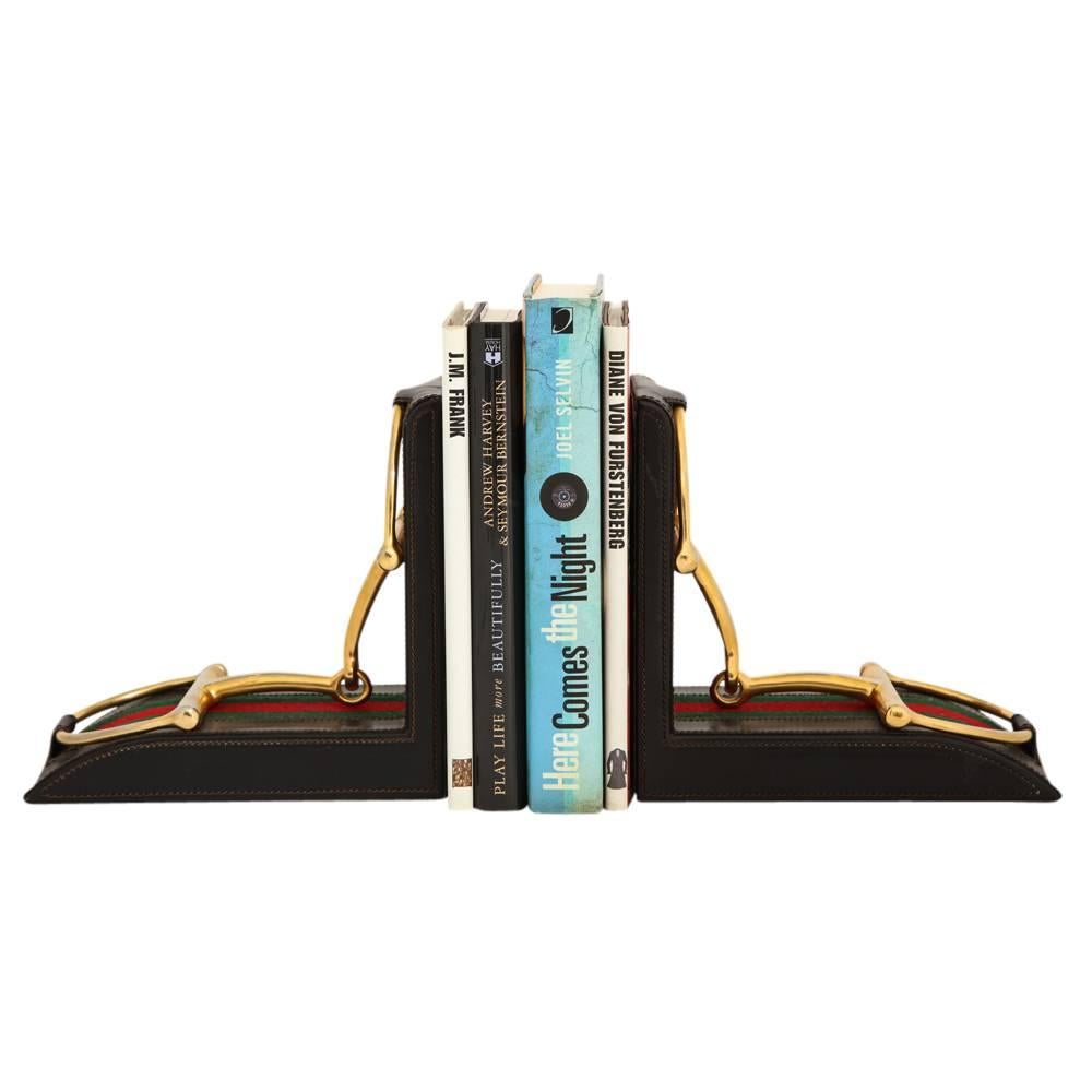 Gucci Horsebit Leather and Brass Bookends Signed Italy 1970's. Brass stirrups attached to the leather slings and mounted on the iconic Gucci green and red fabric which has been stitched on to the leather. Large scale bookends. Marked: 