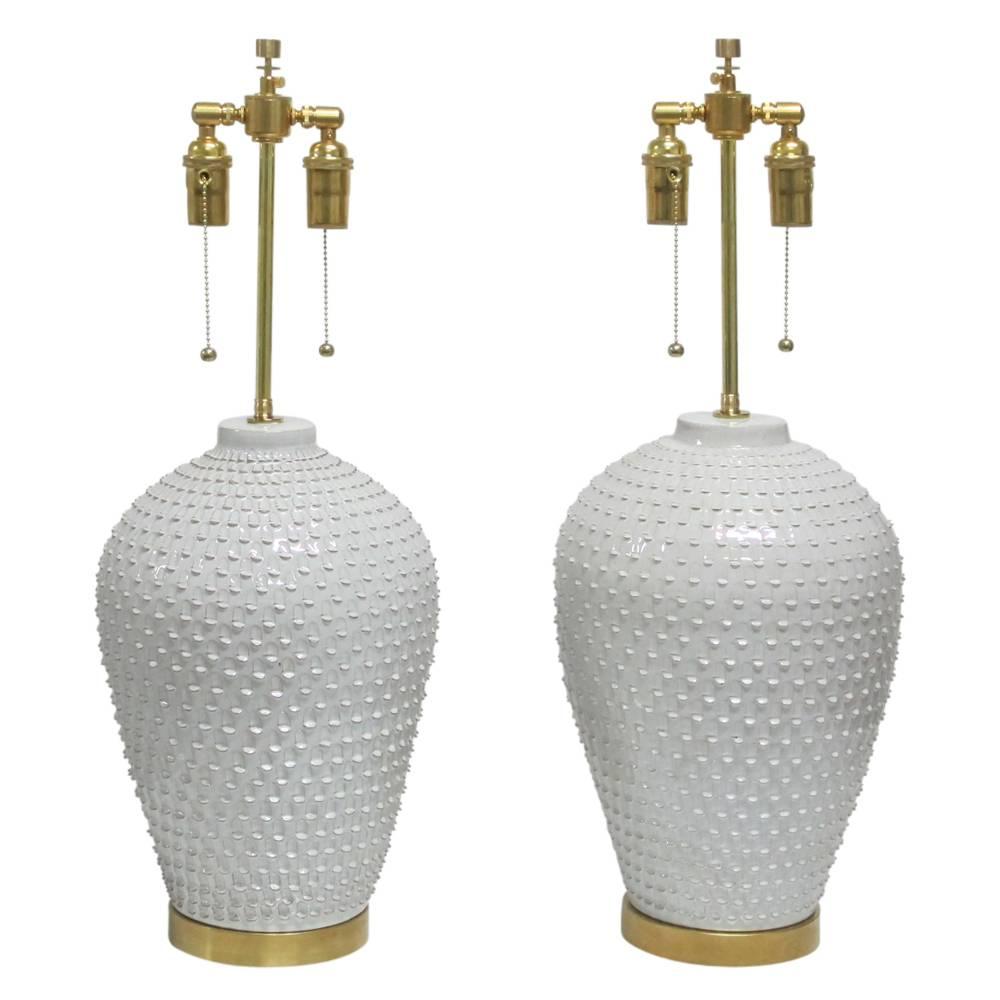 Hegnetslund pair of ceramic table lamps signed Denmark 1960S. White glazed ceramic lamps decorated with textured relief. One lamp is fractionally larger than the other. Underside of one lamp signed: Hegnetslund. The other is signed: Danmark. Rewired