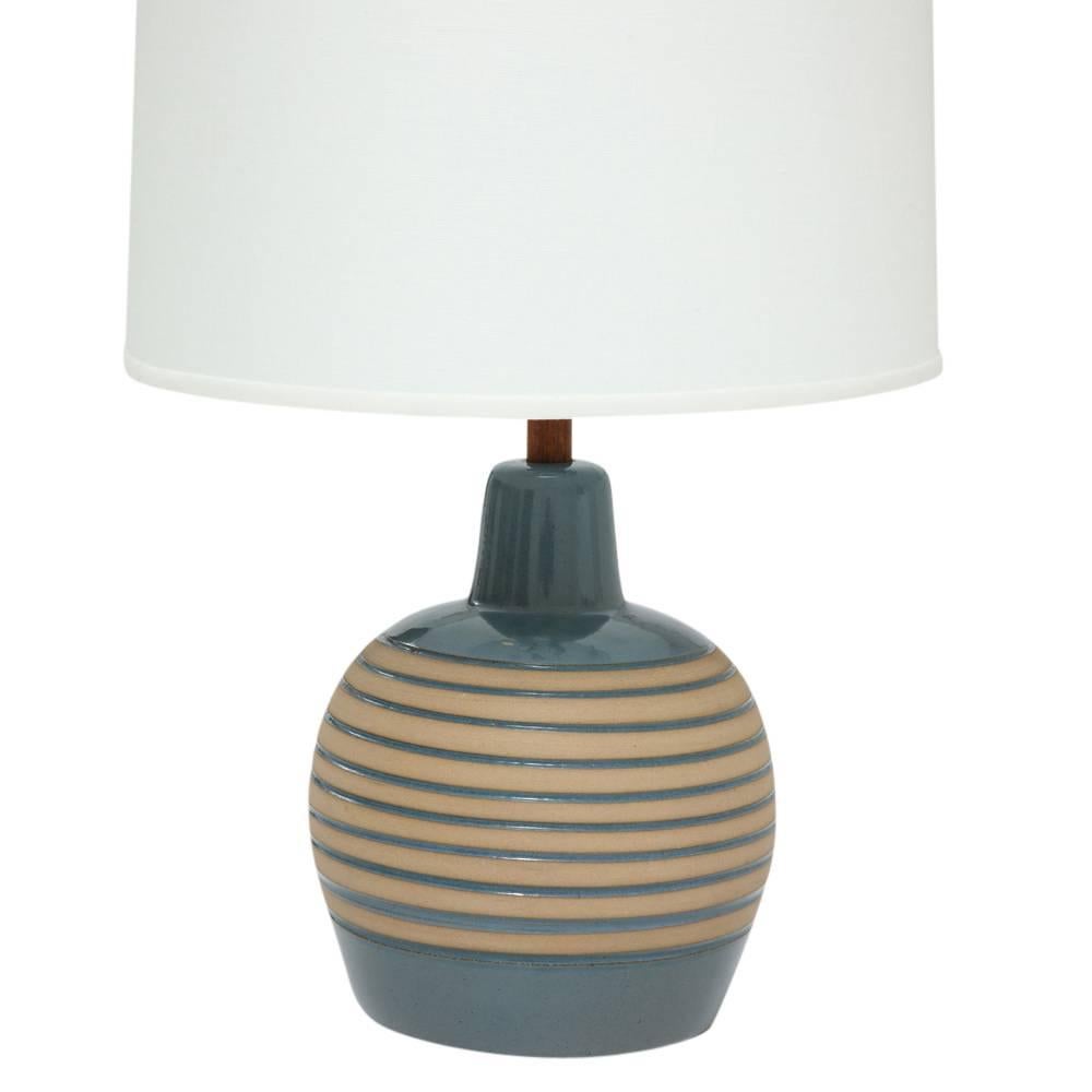 Martz Ceramic Lamp, Blue and Tan, Teak, Signed. Small scale table lamp with semi-matte slate blue glaze with alternating tan horizontal incising. Identified in the Martz Catalog as Model M-51. Lamp retains original teak finial and teak neck post.