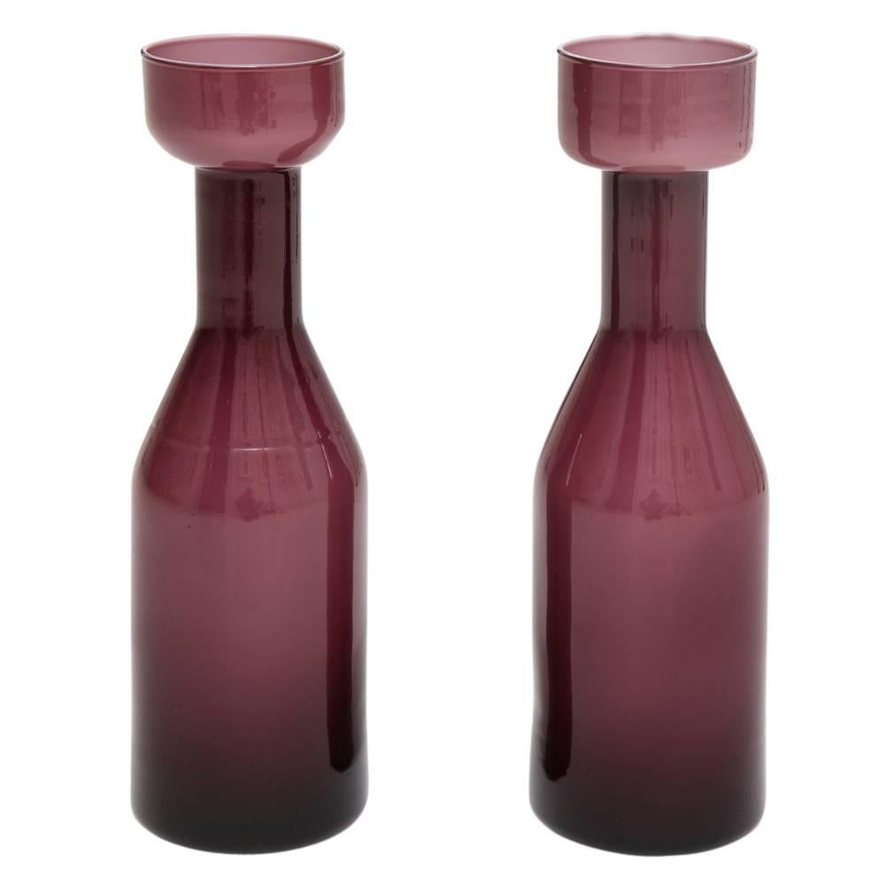AV Mazzega-Vasen, Etui-Glas, lila Amethyst. Paar mittelgroße Glasvasen in Flaschenform. Leichte Verfärbung und Blasenbildung an der Lippe einer der Vasen.
 