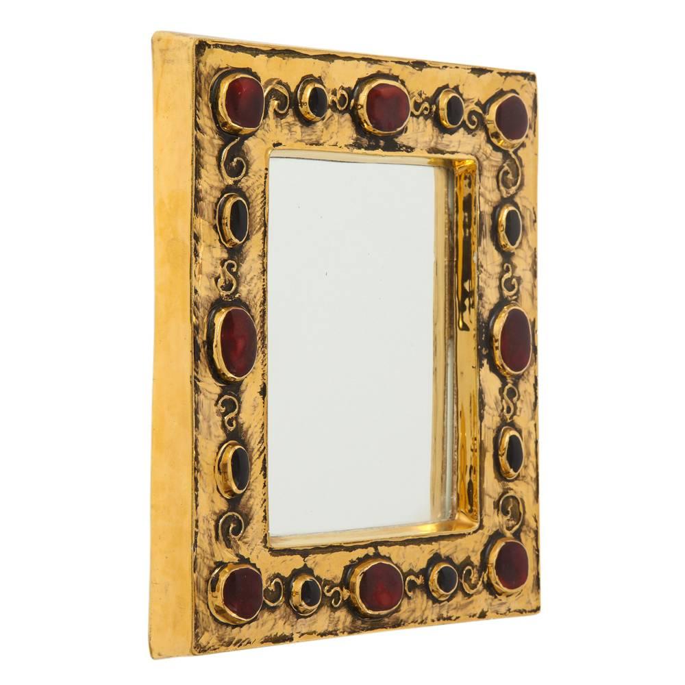 Miroir François Lembo, céramique, or et rouge, bijou, signé. Miroir de petite taille à glaçure dorée, décoré de bijoux incrustés de couleur rouge rubis. Signé F. Lembo avec signature incisée au dos. 

Originaire de Vallauris, François Lembo a