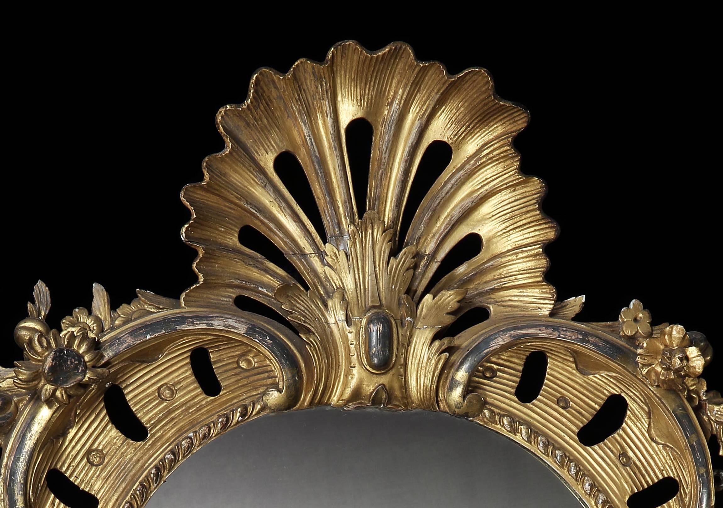 A fine mid-19th century oval giltwood mirror of large-scale with foliate designs to the outer frame, the gilding in two tones, with a pierced scallop shell cresting, with a mercury mirror plate.