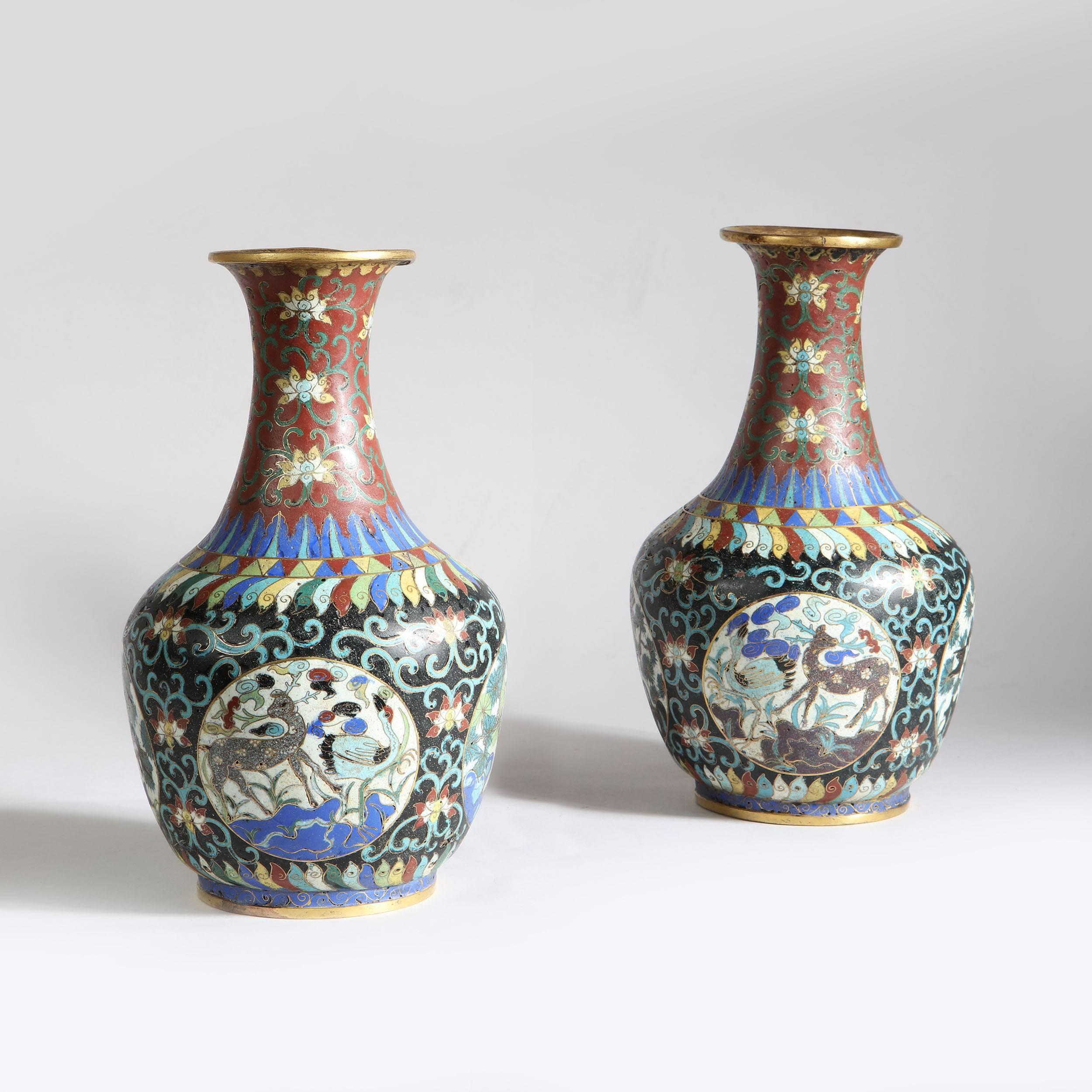 A pair of late 19th century Chinese cloisonne bottle vases, decorated with scenes of deer and birds amongst tropical flora.