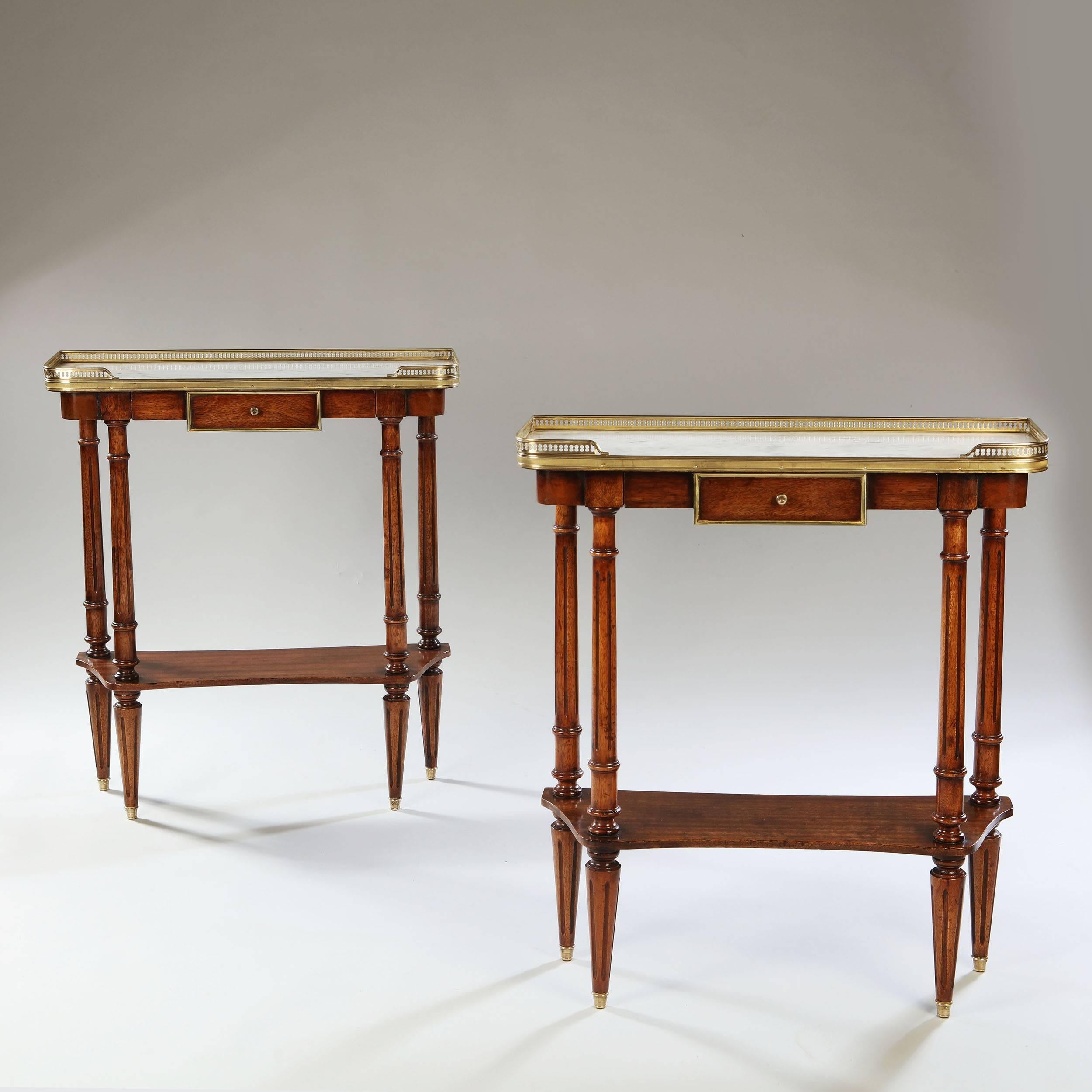 A fine pair of mahogany Empire style side tables with inset white marble tops and brass galleries.