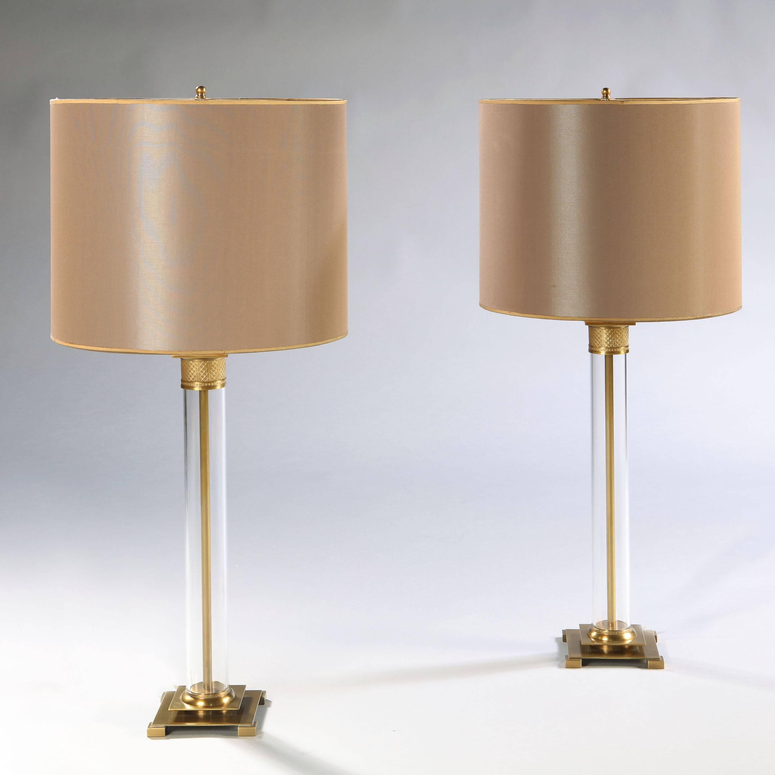 An early twentieth century pair of perspex lamps with brass mounts, telescopic double bulb fittings and brass finials, with bespoke silk shades.