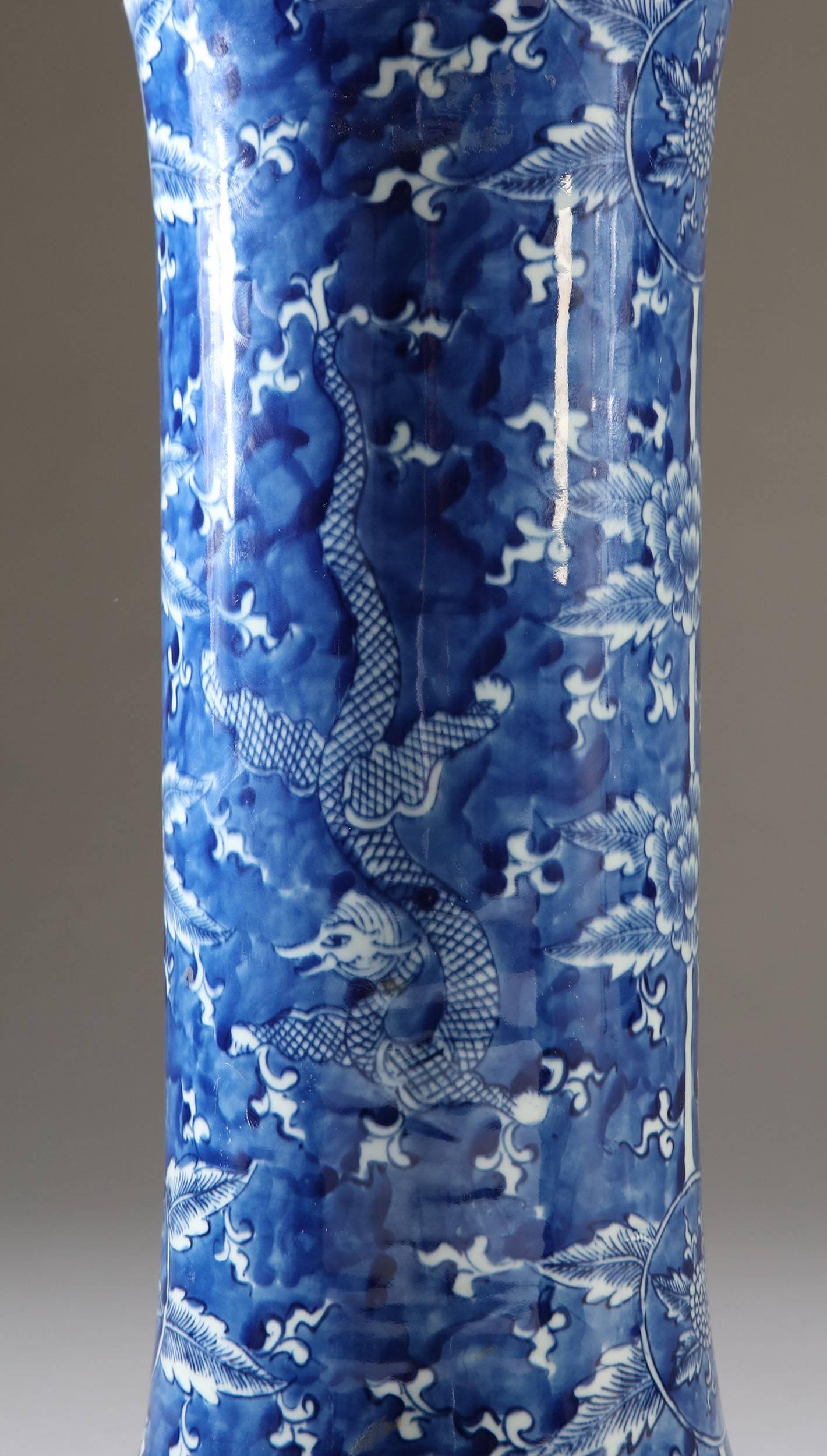 A pair of 20th century blue and white Chinese vases, of trumpet form, decorated with floral motives and dragons. Now converted to lamps.