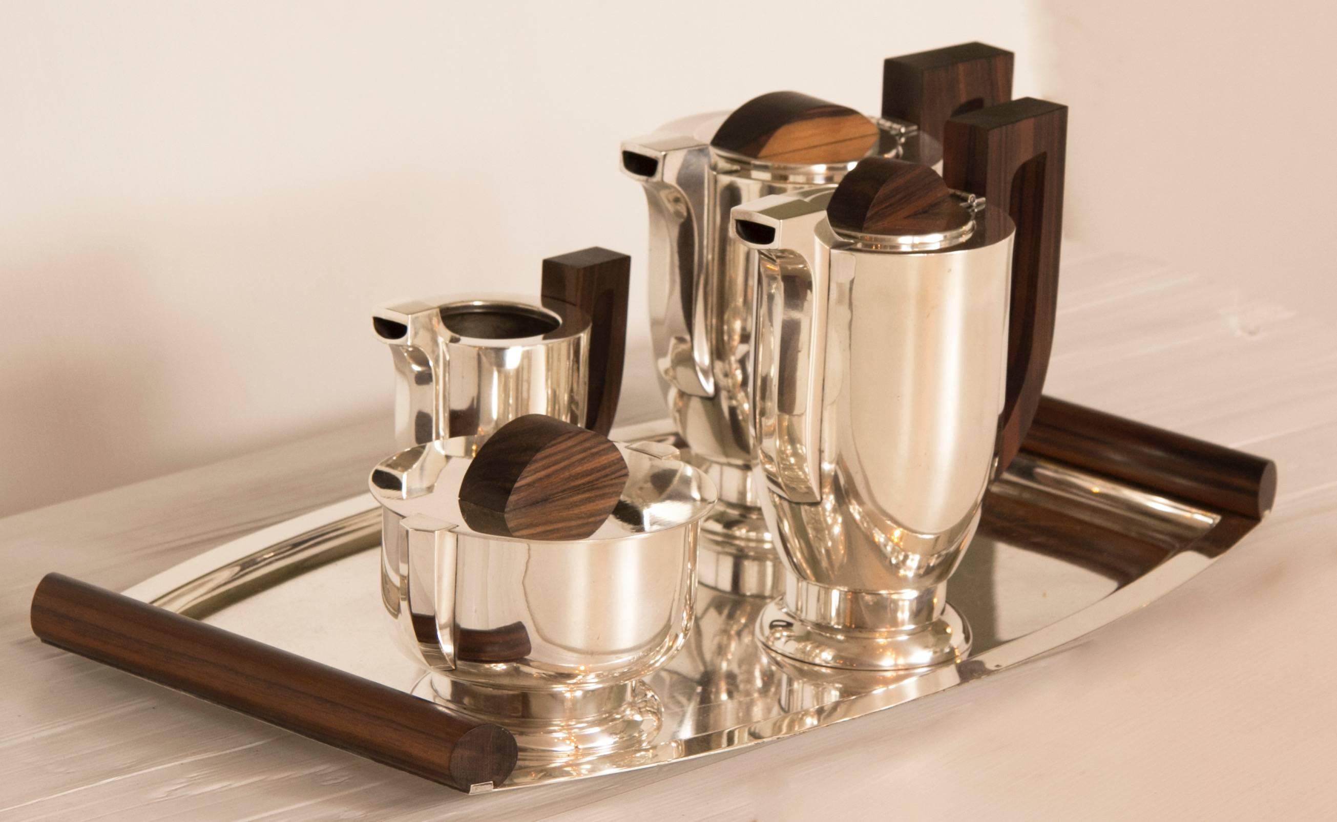 Art Deco silver plate tea set on its original tray, tea pot, hot water pot, milk jug, covered sugar bowl and tray.
Measures: Tray - H: 4 cm W: 51 cm D: 32 cm 
Tea Pot - H: 21 cm W: 19 cm D: 11 cm
French, circa 1930.