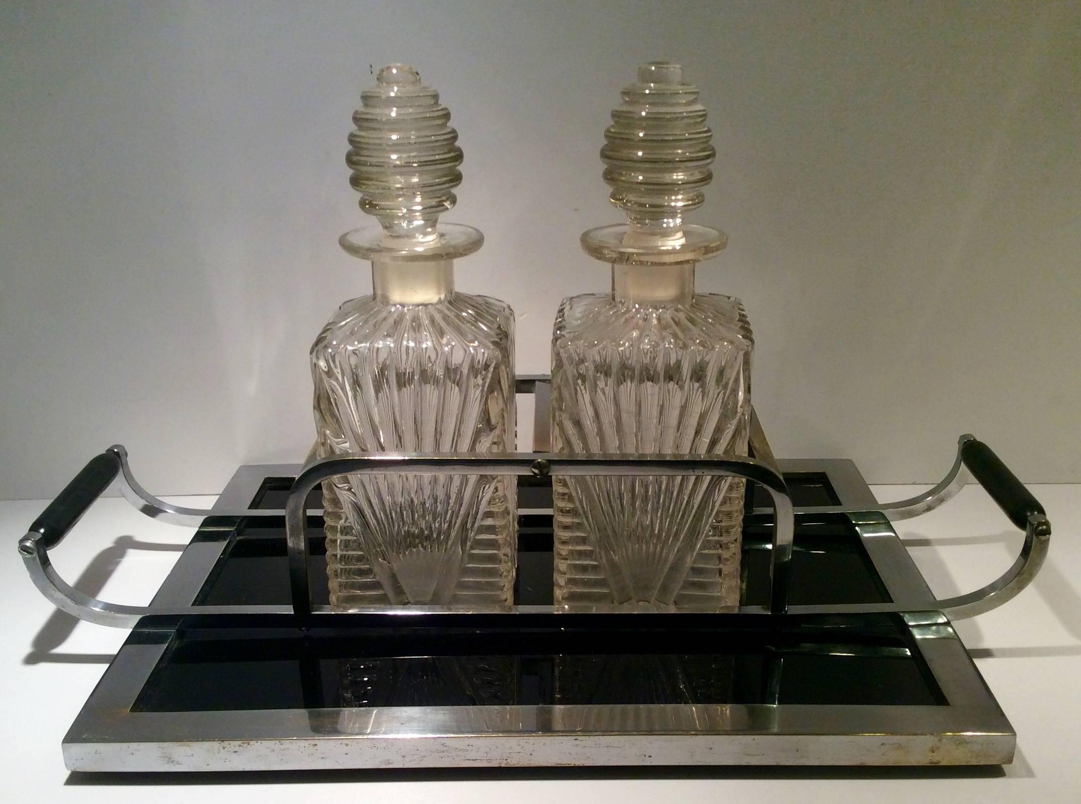 Art Deco tantalus, stunning pair of Art Deco decanters on a fitted chrome tray with black bakelite base and handles.
The tray is 46 cm across at the handles.
The tray base is 37 cm W, 28 cm D and 2 cm thick.
Each decanter is 25 cm H, 9 cm W, 9 cm