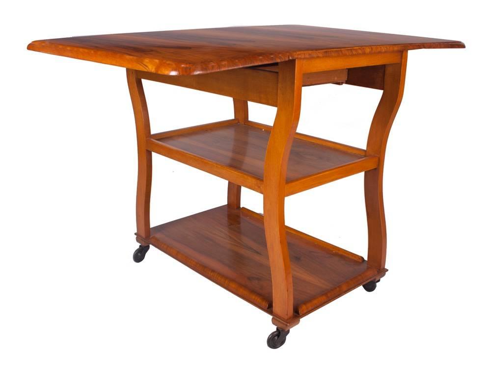 Art Deco drop-leaf table trolley with single drawer.
Walnut Art Deco table trolley, very useful item on casters and drop leaf sides which turns this little trolley into a very useful table, also has a single drawer to one end.
Measures: H 73 cm, W