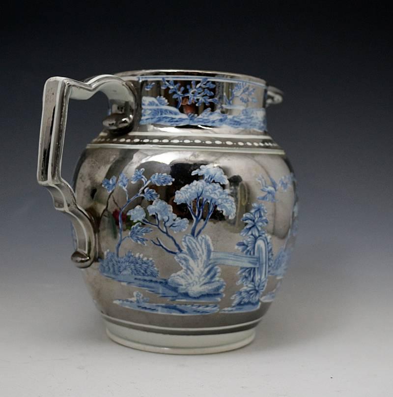 A fine and rare larger than normal silver luster pottery pitcher with an underglaze blue and white transfer print of a romantic idealized picture of a rural sporting scene with hunters and dogs in the 