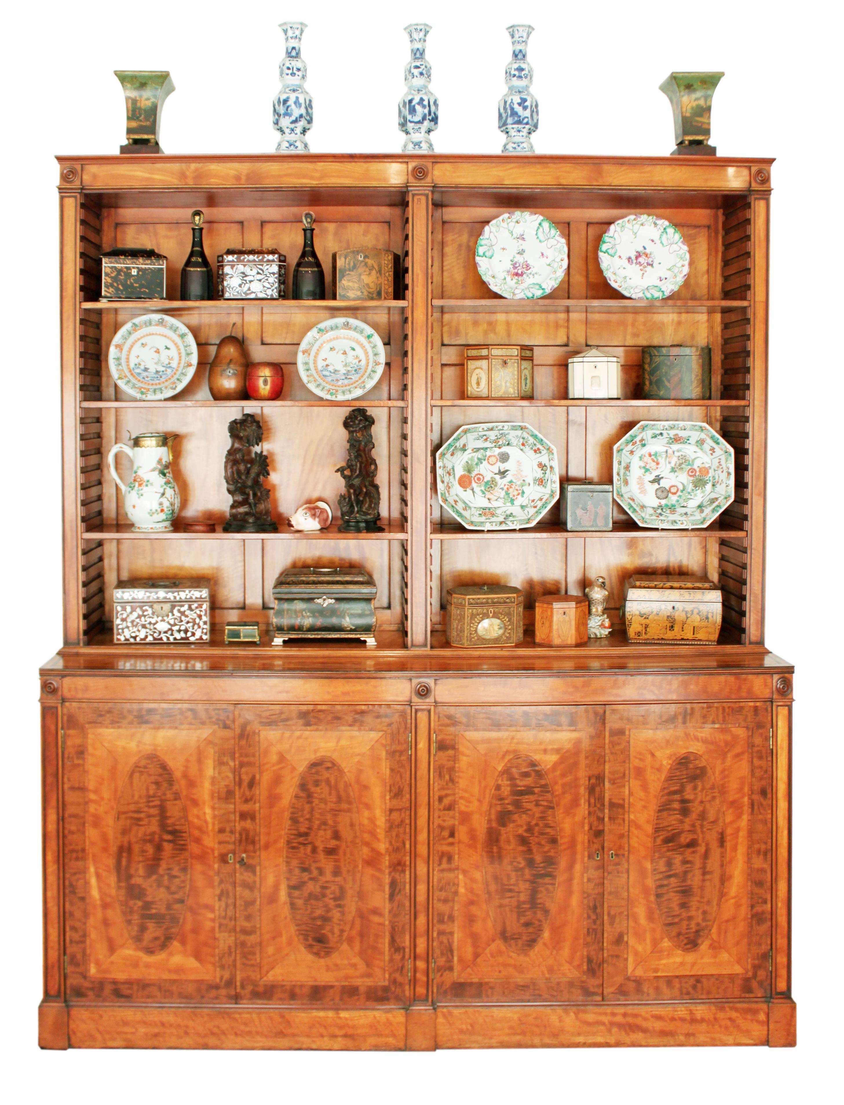 A fine quality George III bookcase in satinwood the doors crossbanded and inset with ovals in an exotic timber good architectural detail with pillasters inset with roundels the upper backboards and shelves also in satinwood.