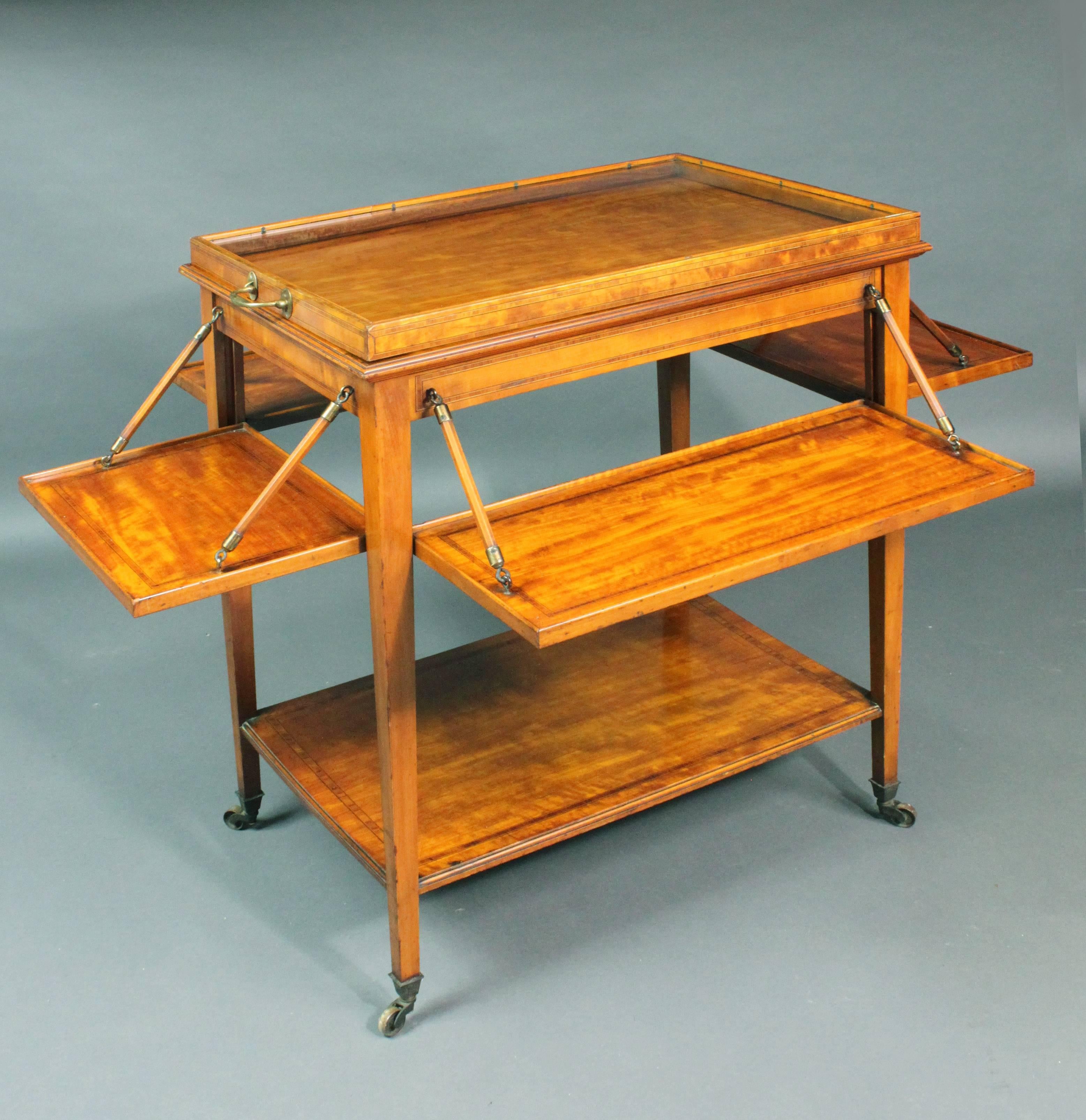 An exceptional tea trolley in satinwood of a good color and patina; a tray flaps out on each side to hold sandwiches and cakes and there is a removable glass bottomed tray on the top.

Width when trays opened out 39