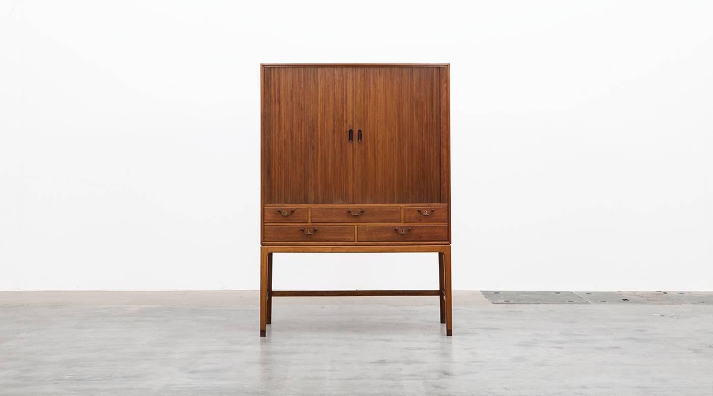 This stunning early example of Ole Wanschers work from 1948 offers long legs and an interior with practical shelves and five drawers for a generous amount of storage space. The highboard comes in mahogany and stand on brass feet. Manufactured by