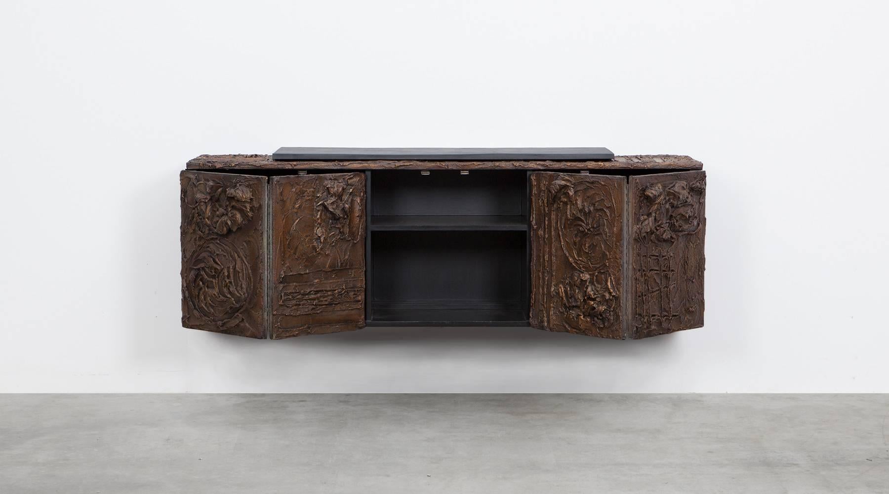 Gorgeous wall-mounted sideboard designed by Paul Evans in 1968, executed in hand-sculptured bronze resin with dramatic, deeply incised designs throughout. The Sideboard features bi-fold doors and integrated, hidden door pulls. It finishes with a