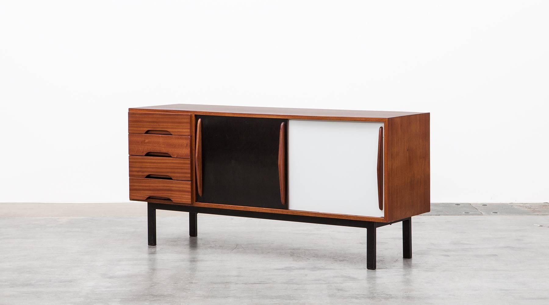 Beautiful and really rare Charlotte Perriand sideboard edited by Steph Simon. This piece is made out of mahogany and comes with four drawers and two laminate sliding doors in black and white. The sideboard is in very good original condition with