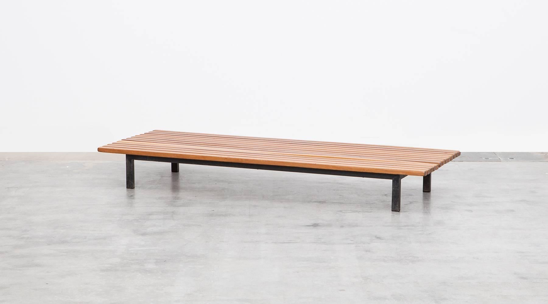 The bench designed by Charlotte Perriand comes on a black lacquered metal frame and has wonderful patina on the legs and on the lattes which are stained teak. The unusual height gives the special feature to that object. This model is the smaller