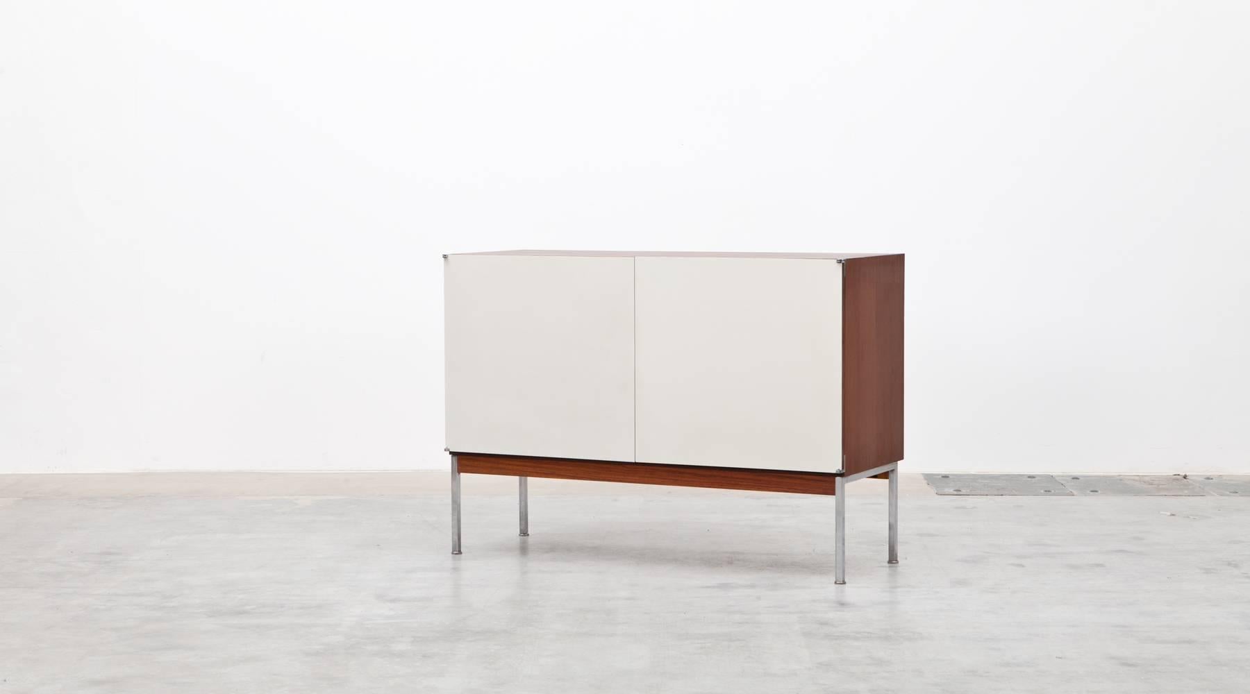 The sideboard designed by Antoine Philippon and Jacqueline Lecoq comes with white laminated two doors. The corpus is rosewood and stands on chromium plated steel frame. Manufactured by Bofinger.