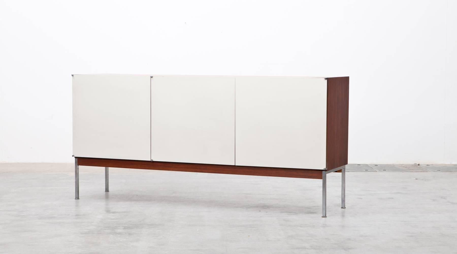Sideboard with three white laminated doors designed by Antoine Philippon and Jacqueline Lecoq. The corpus is rosewood, the inlay features a big storage area with shelves on one side and additional four drawers on the other side. Manufactured by