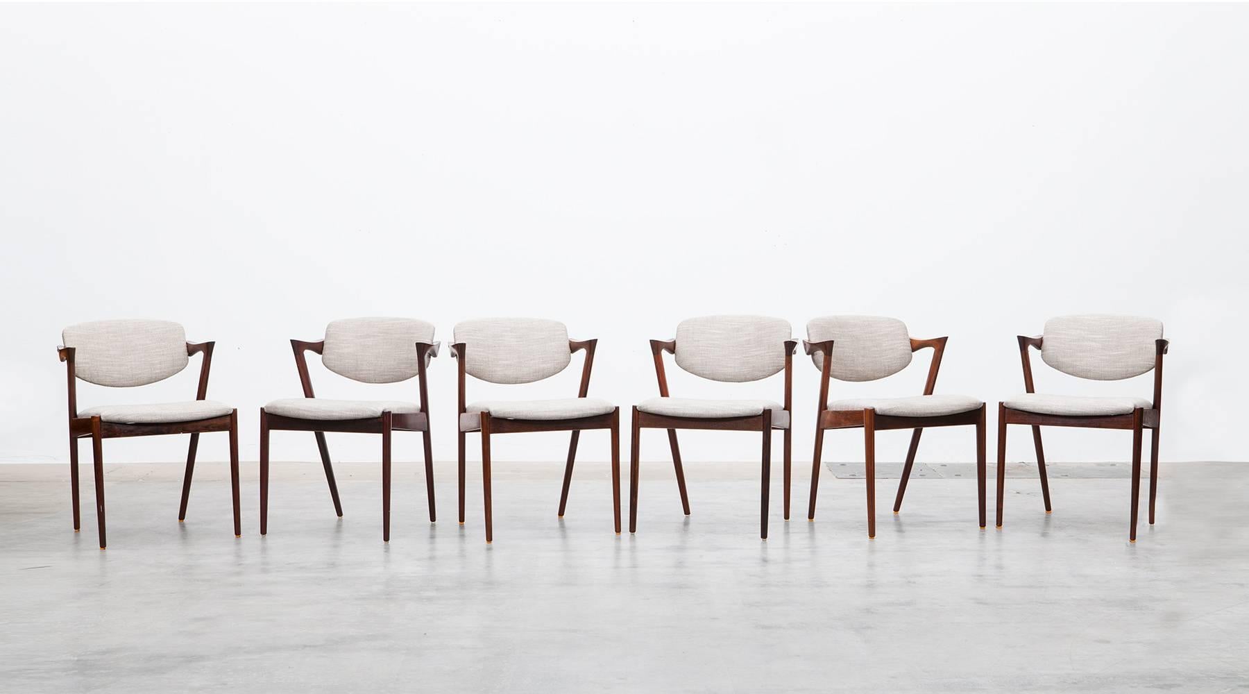 Wonderful Mid-Century Kai Kristiansen dining chairs in wood comes in a set of eight. The wooden backrest is beautifully curved with small arm details. The conditions are very good, the seats newly upholstered with high-quality fabric. Manufactured