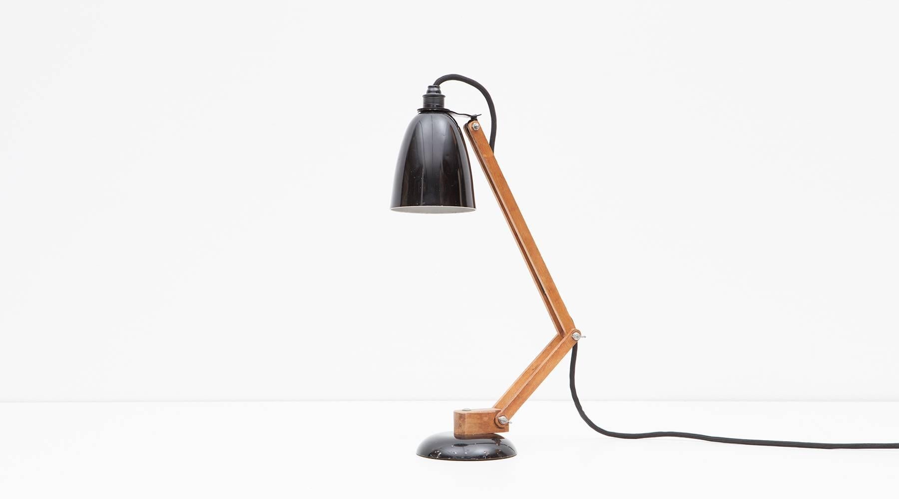 A rarely available and highly sought table lamp by Terence Conran. The adjustable shade made of black lacquered aluminum is hold by an adjustable pole in wood and stands on black lacquered metal base. The contrast of the materials gives the lamp a