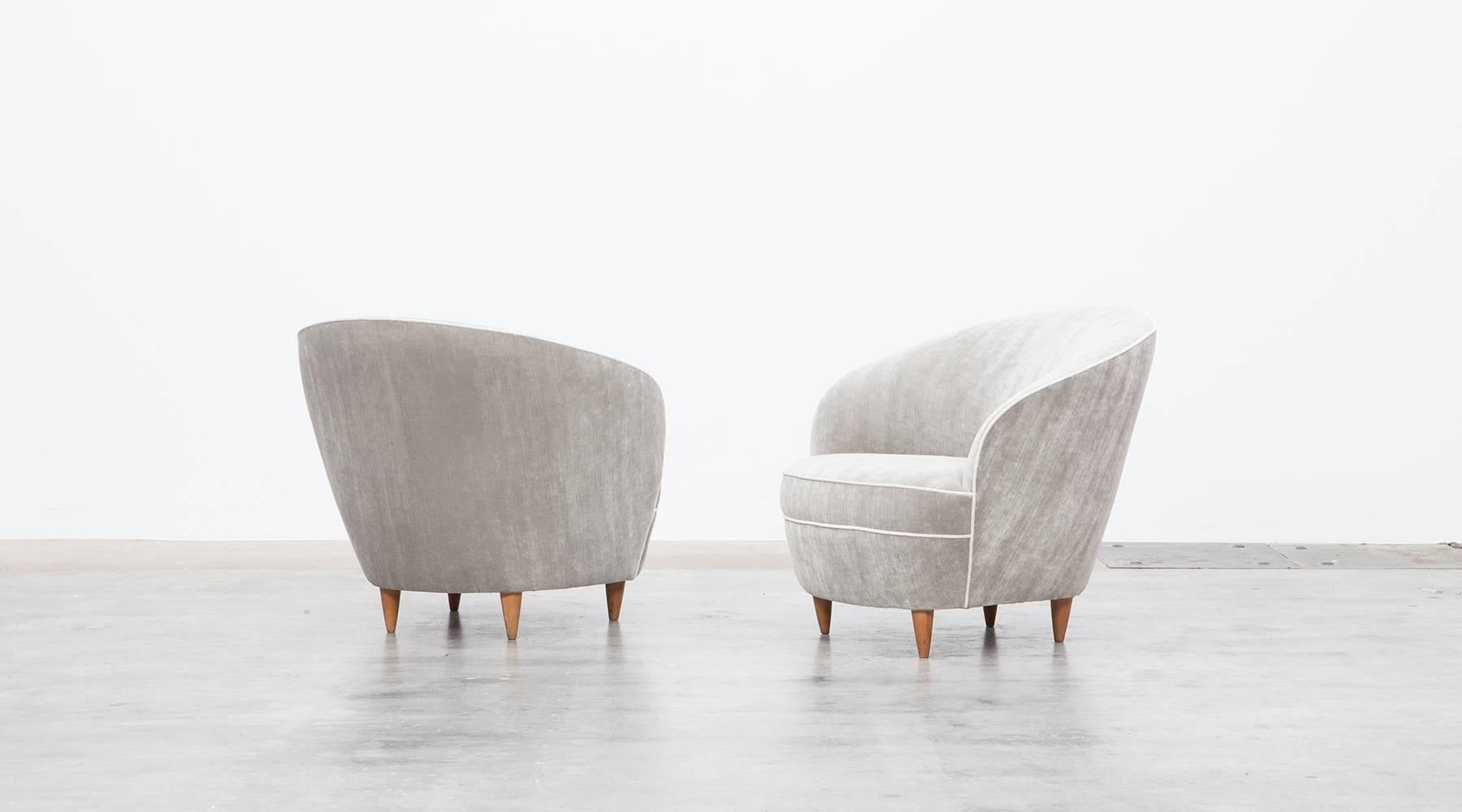 A pair of Mid-Century Italian lounge chairs in the style of Ico Parisi. Sensual curves, elegantly tapered legs gives the chairs a sculptural look. The chairs are newly upholstered with high-quality fabric. Matching sofa available. Manufactured in
