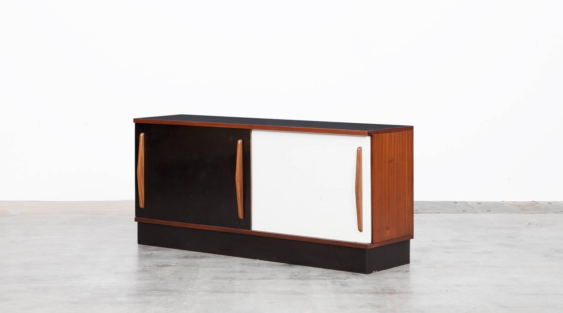 Beautiful and really rare Charlotte Perriand sideboard edited by Steph Simon. This piece is made out of mahogany and comes with two shelves and two laminate sliding doors in black and white. The sideboard is in very good original condition with
