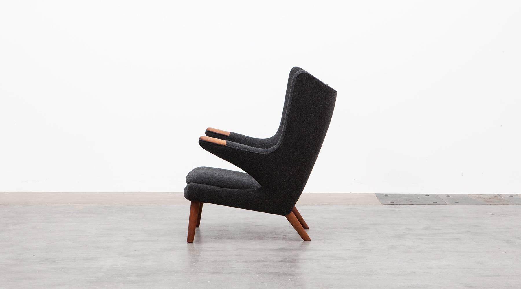 Wonderful original Papa Bear lounge chair designed by Hans Wegner. It is in perfect condition although the wood is reworked. It comes in a high-quality dark grey woolen fabric and is recently upholstered. The legs and nails are teak. Manufactured by