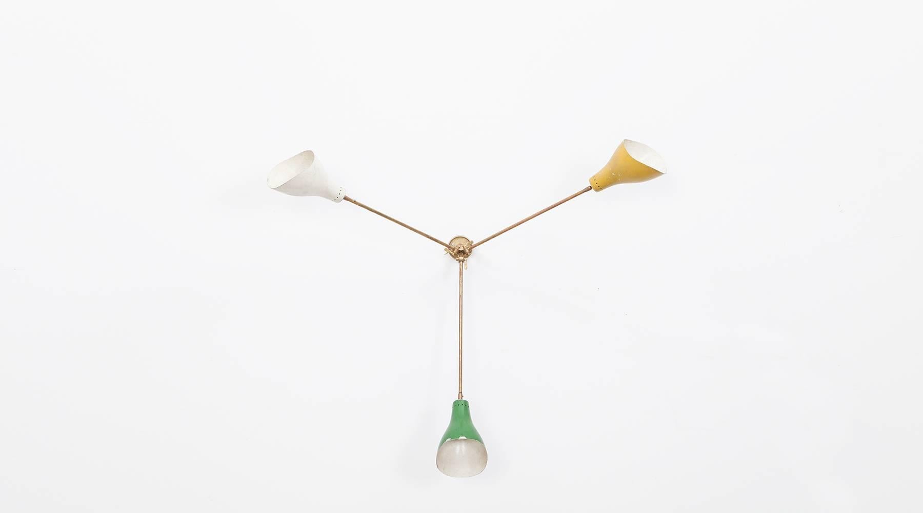 Delightful three-arm adjustable wall or ceiling lamp by Stilnovo. Features three colored shades in bright yellow, green and white. The lamp comes in exceptional vintage condition. Manufactured by Stilnovo. 

The Italian lamp design movement of