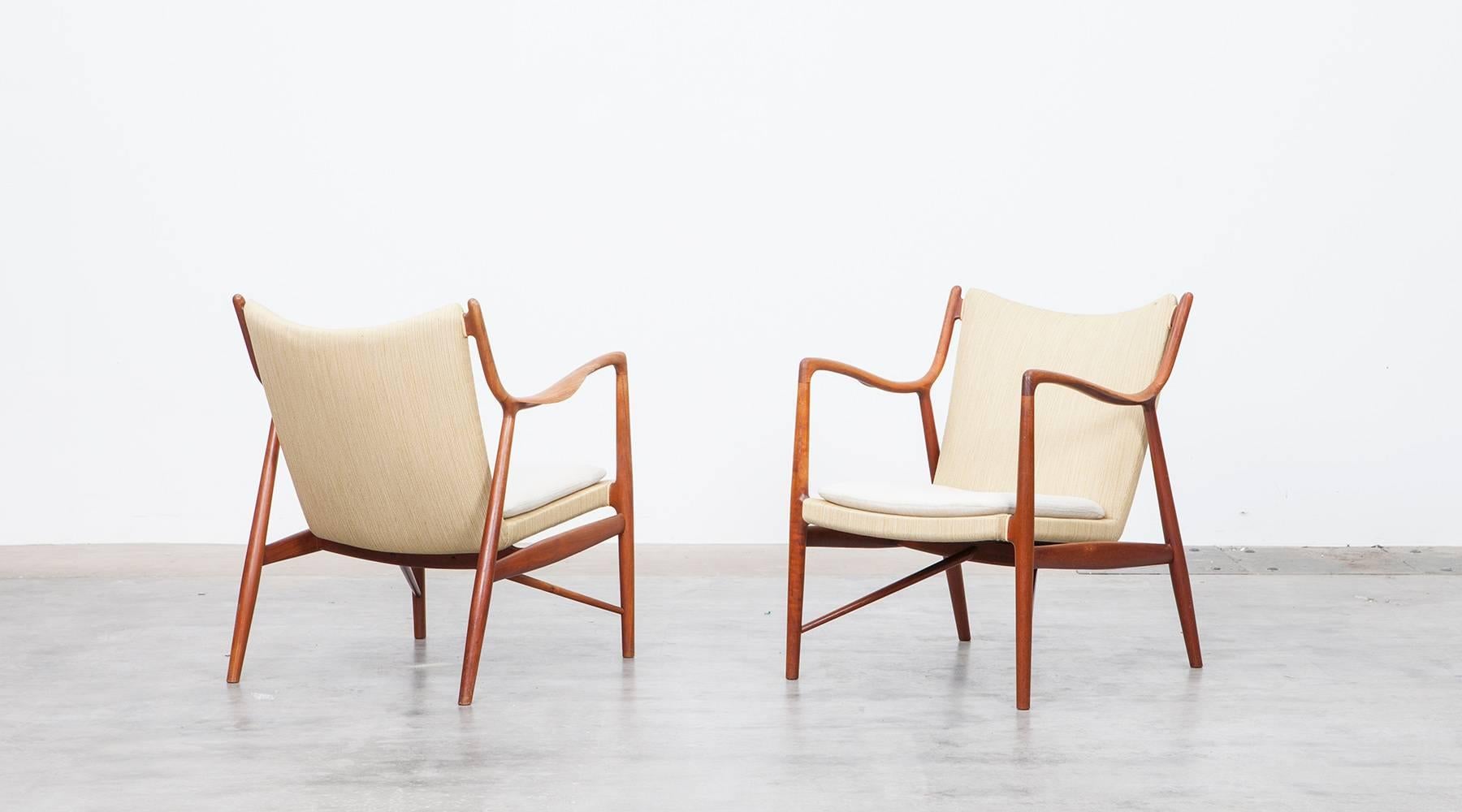 A pair of Finn Juhl Lounge chairs in teak with sculpted sling arms, loose seat cushions for very comfortable seating. The wooden frames comes in very good original conditions. Manufactured by Niels Vodder.
