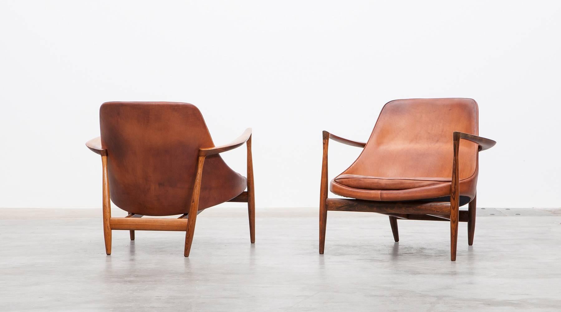 Wonderful examples of Ib Kofod-Larsen lounge chairs in wood with amazing patinated cognac leather. The lounge chairs were created in 1956. Manufactured by Christensen & Larsen.