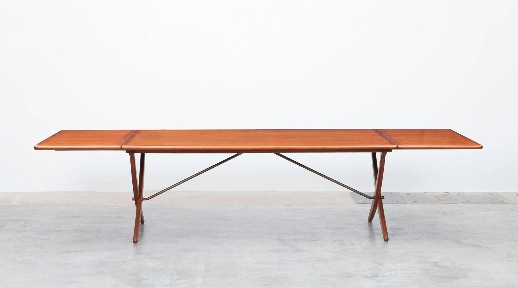 Stunning, solid dining table designed by Hans Wegner comes with a teak top and two wings which can be folded down. The crossed legs construction gives to the table a good stability. The table is extendable to a maximum length of 310 cm. The details