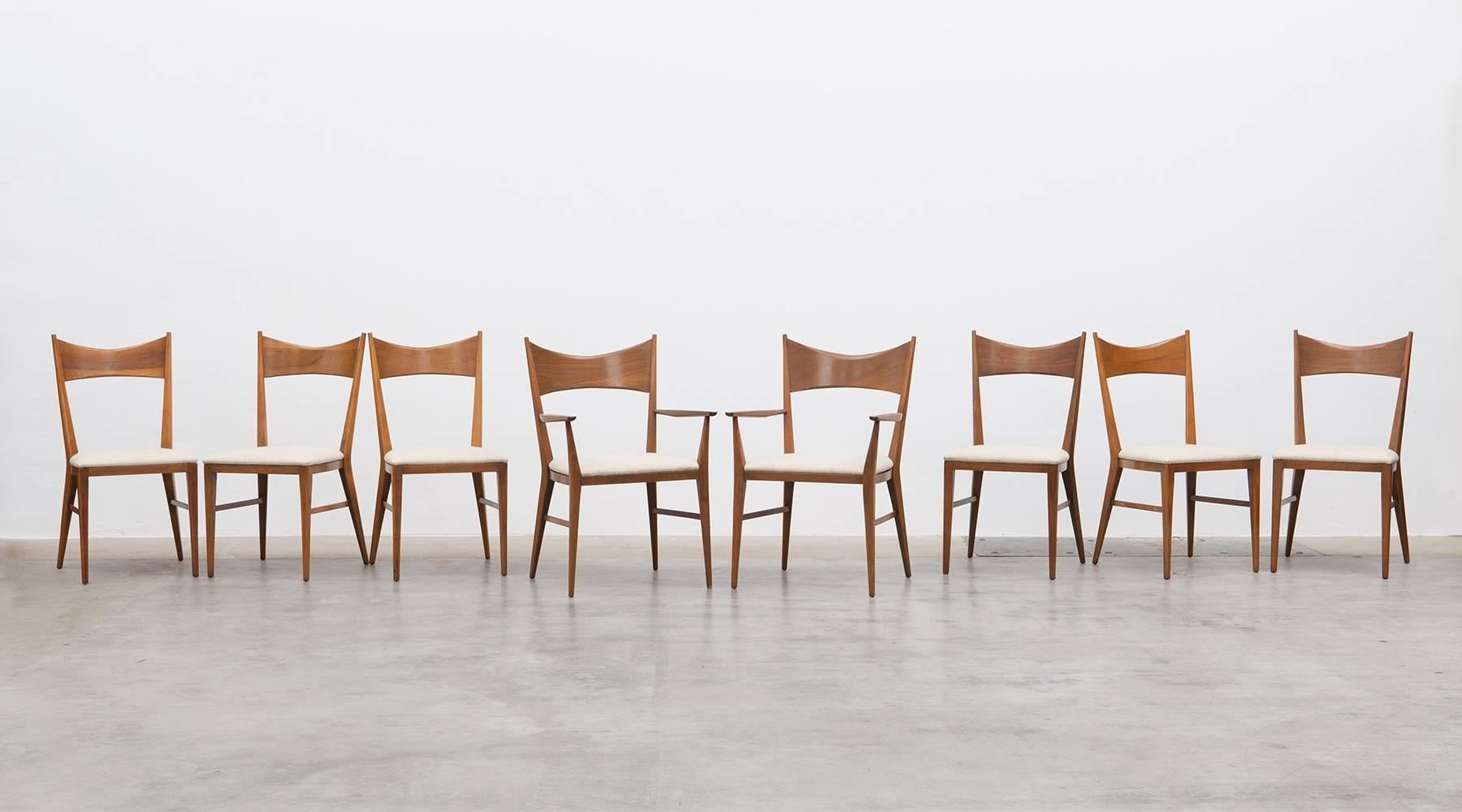 Set of eight dining chairs designed by American Paul McCobb. Nicely curved backrests, but still minimalistic design in walnut. The seat comes with light, warm fabric and two of the chairs comes with armrests. Manufactured by Calvin.
 