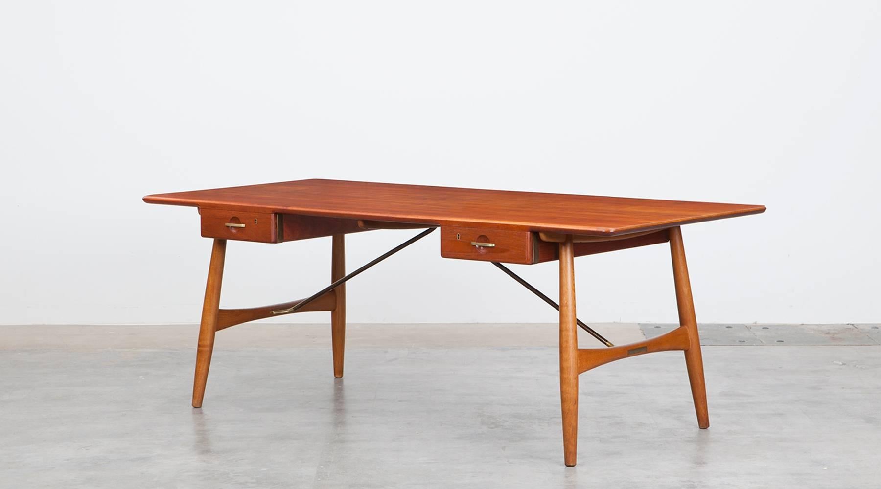 Stunning, solid desk designed by Hans Wegner comes with a teak top on four oak legs and frame. The table comes with two drawers. The details on frame and drawers are brass. Manufactured by Johannes Hansen.

Wegner's work is a lifelong quest to